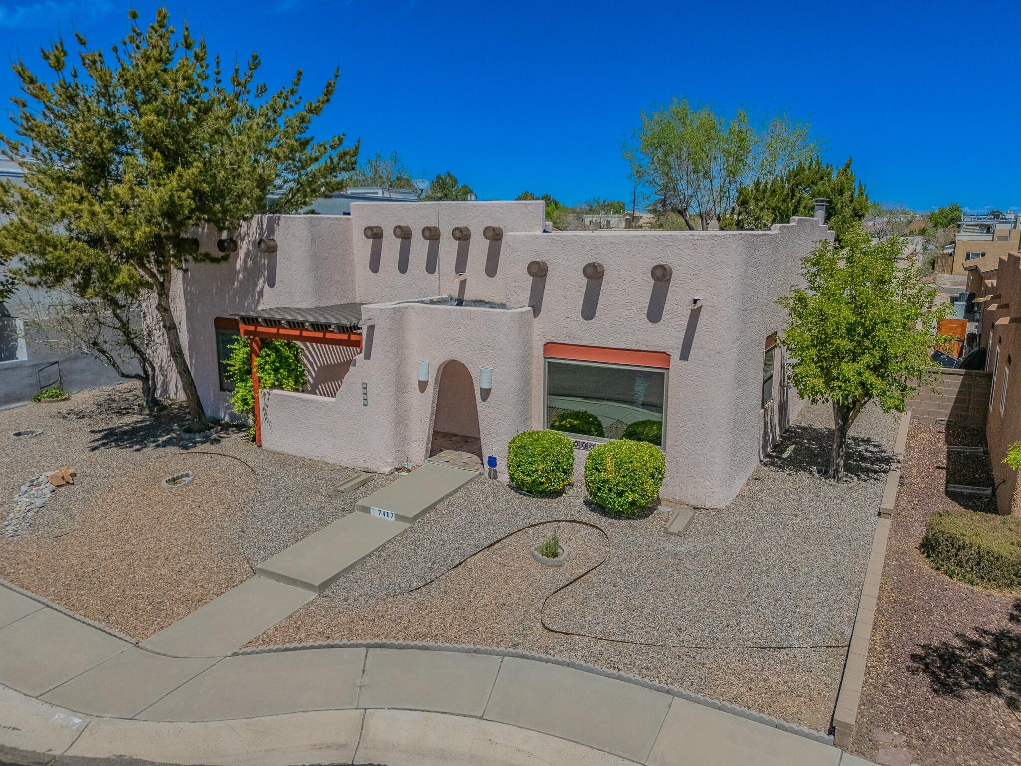 Step into Southwest charm in this adorable one-story Pueblo gem in lovely Laurelwood! A colorful entry welcomes you into a sunny, cheerful great room featuring classic Saltillo tile, laminate floors, an exposed adobe pony wall, and soaring viga beam ceilings. The updated kitchen shines with granite counters, cabinet pullouts, soft-close drawers, and sleek stainless appliances. Cozy up by the kiva gas log fireplace with a built-in banco--perfect for dreamy evenings! The spacious owner's suite boasts a gorgeous bath, while a private backyard oasis features lush landscaping and lawn. Enjoy refrigerated A/C, a side patio retreat off a guest room, and a garage with tons of storage. Pueblo perfection awaits!