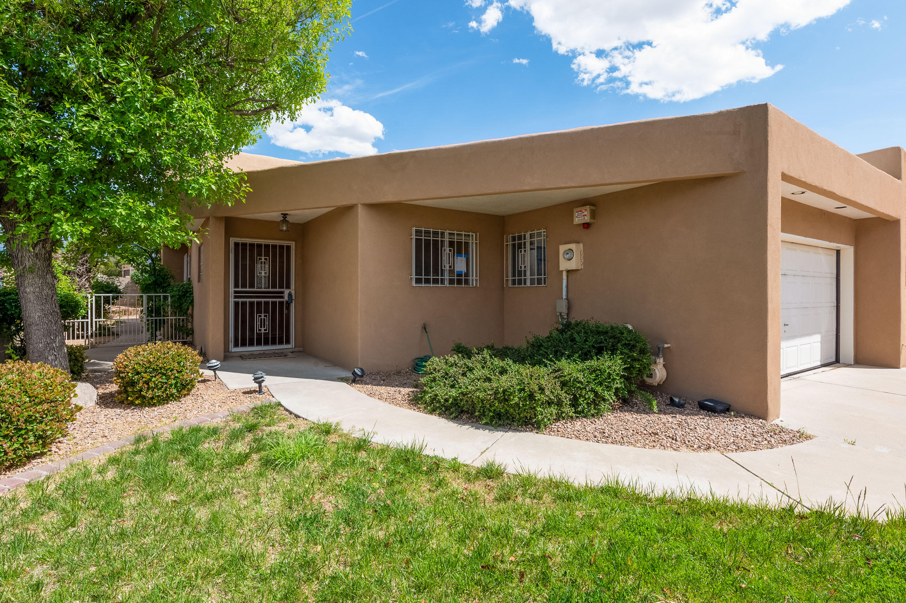 Location, Location!! Charming one owner  townhome in Bear Canyon with wood, tile and laminate floors, tall ceilings, open floor plan, dining room, large living room with raised ceilings, fireplace and clerestory windows. Separate office/studio and 2 bedrooms . New TPO roof in 2025.  Private side yard and back patio with mature trees. Close to walking trail around ABQ Academy.  Move-in ready!