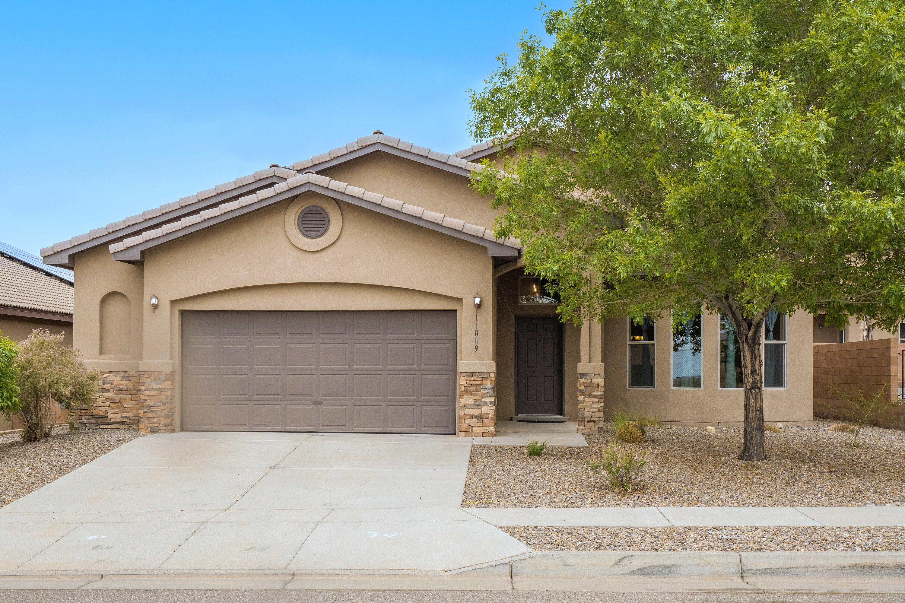 Charming Raylee home in Popular Volterra Subdivision of Juan Tabo Hills! Light-filled and open, this well-maintained home features a spacious great room with gas fireplace, clerestory windows, and coffered ceilings. The kitchen offers granite counters, an island, walk-in pantry, stainless appliances, vent hood, and recessed lighting. Dining area opens to a covered patio and backyard--great for entertaining. The private owner's suite includes dual vanities, a garden tub, and a large walk-in closet. Additional features: stacked stone accents, ceiling fans, solar panels, and a 570 sq ft garage. Close to shopping, Sandia Labs and Kirkland AFB , UNM. Move-in ready and full of natural light--come see it today!