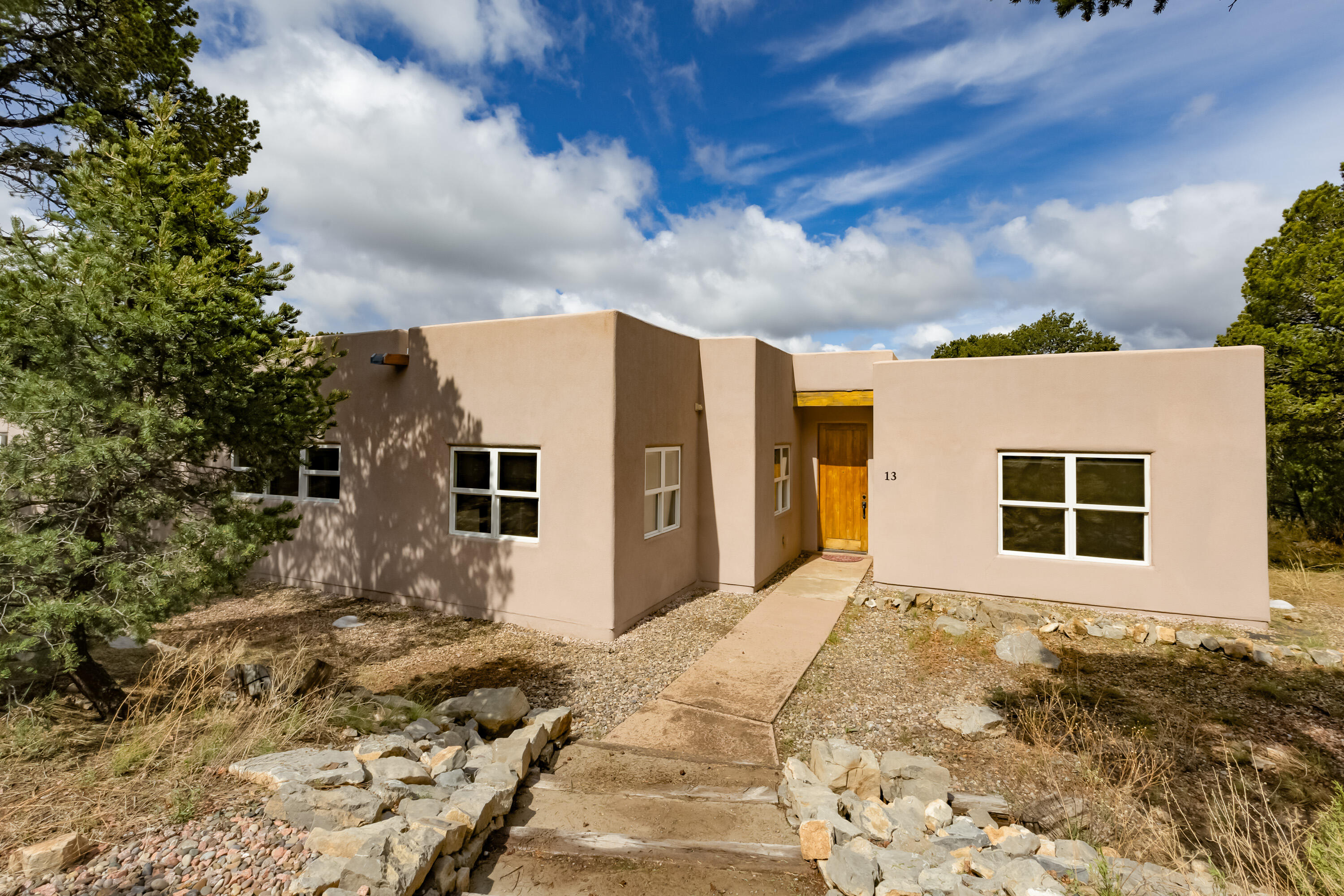 Escape to peaceful East Mountain living just 20 minutes from Albuquerque! This beautifully crafted single-story home offers stunning mountain views, warm wood beam ceilings, and polished stained concrete floors throughout. The open layout includes a gourmet kitchen with granite countertops, stainless steel appliances, a large island, and a spacious walk-in pantry with electrical outlets. Relax on the patio or in the hot tub while soaking in the natural surroundings. Set on 3.39 private acres, there's room to breathe, explore, and unwind. The property includes a 2-car attached garage and a versatile detached 2-car garage/workshop with 220 power, pellet stove, and plumbing--ideal for creative or hands-on pursuits. Serenity meets function in this mountain retreat!