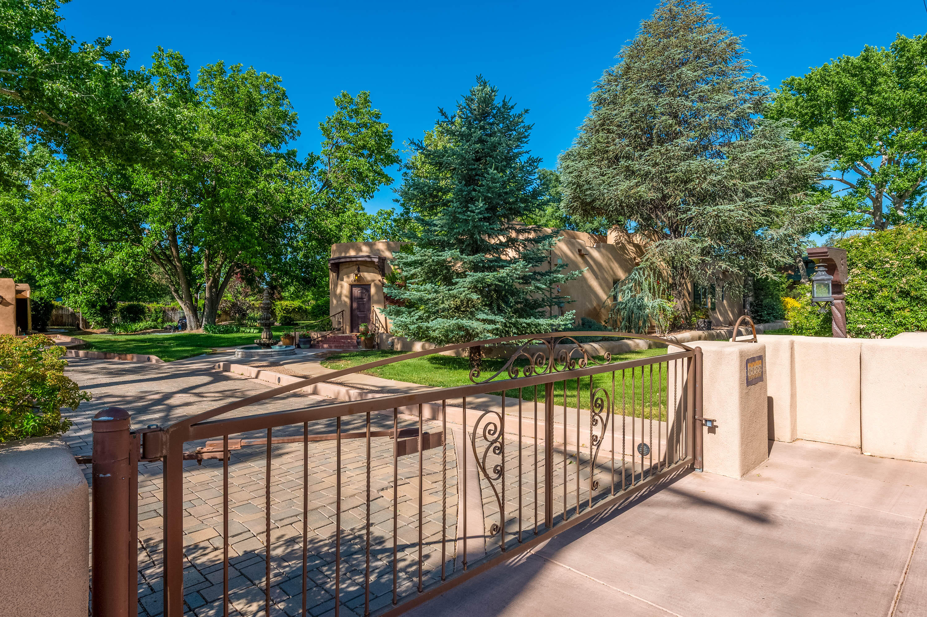 An exquisite work of art, this multigenerational North Valley property is in the perfect location! Spacious pueblo home and guest casita on a lush, tree-shaded acre with expansive gardens beneath towering cottonwoods. This sophisticated property includes artistic hand-crafted details and lovely, well-proportioned rooms.  Beamed ceilings, kiva fireplaces, and special details abound.  An irrigation well keeps everything green!  Walk to the Los Ranchos Farmer's Market or to a wine tasting at Casa Rondena. Historic Los Poblanos is a stone's throw away.  Beyond the gated grounds are miles of walking paths, and a peaceful rural vibe in the heart of Los Ranchos.  An absolutely charming home with room for everyone!