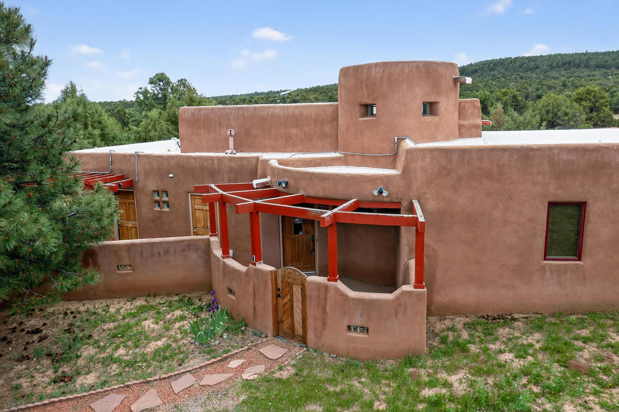 Tucked away in the scenic woodlands of Tijeras, this 3-bed, 2-bath pueblo-style home blends timeless Southwest design with modern sustainability. At 1,722 sq. ft., it showcases hand-plastered walls, exposed adobe accents, kiva fireplace, solar tubes, and stained concrete and brick floors--offering warmth, character, and efficiency at every turn. Designed for low utility living, the home features solar panels and natural climate control elements like passive solar and a trombe wall. An additional flex space perfect for a home office or creative studio. Set on nearly 6 wooded acres, the property offers privacy and plenty of space for horses, gardens, or even a future casita. Whether you're seeking a greener lifestyle or simply an escape from city life, this serene homestead is a rare find.