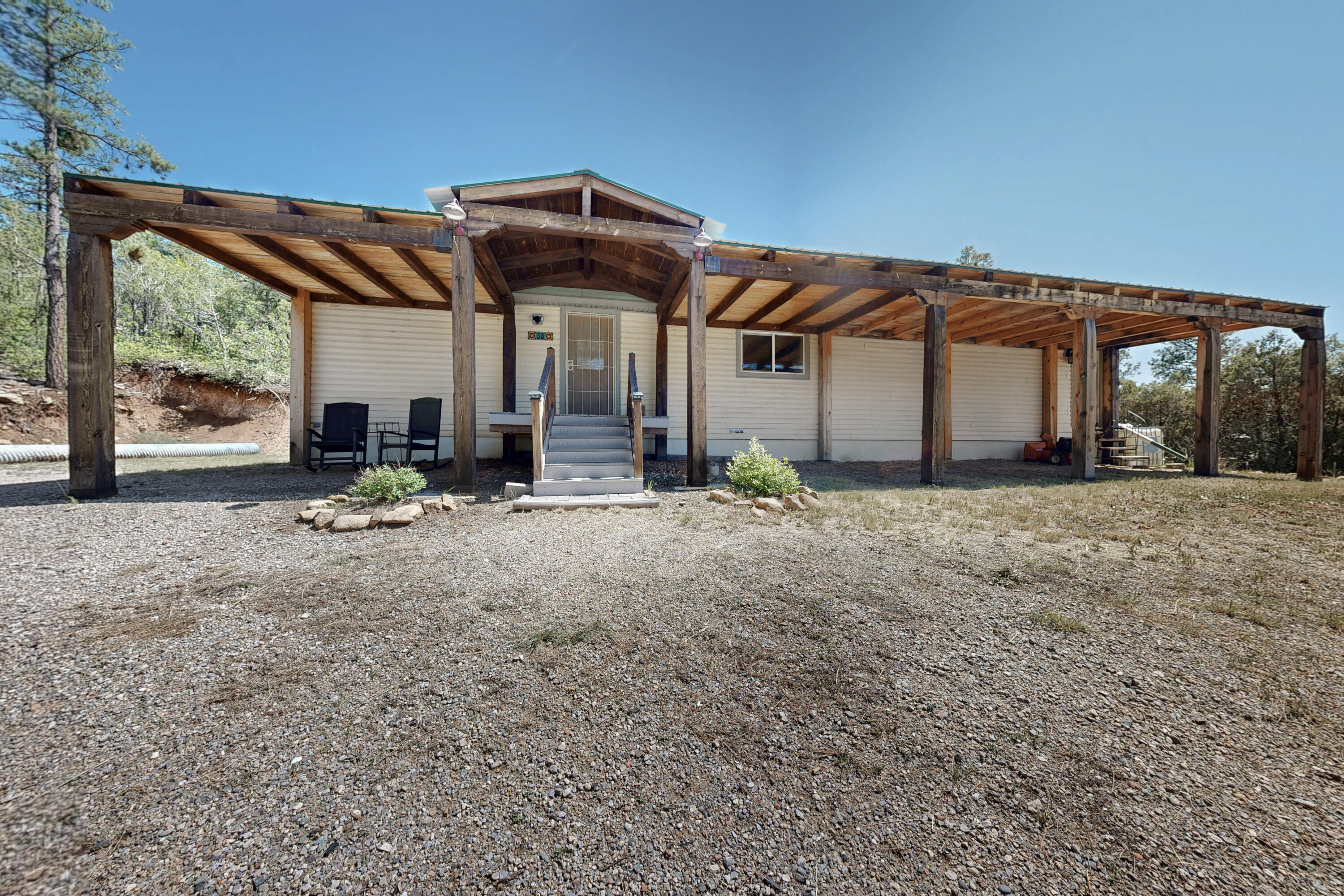 Tucked into 5 scenic acres in the Carolino Canyon community, this beautifully updated home blends privacy, nature, and neighborhood charm. Surrounded by pines and pinon, enjoy mountain views, peaceful seclusion, and nearby hiking. Inside, a spacious country kitchen and bright open living room features large updated windows that fill the space with natural light. The large primary suite offers outdoor access to the side yard and a cozy fireplace-style feature. Two other good-sized bedrooms and an updated bathroom complete the well-designed floor plan. Vinyl plank flooring, slate countertops, solar tubes, a pellet stove, and a metal roof add comfort and style--plus a large covered front patio for relaxing outdoors.