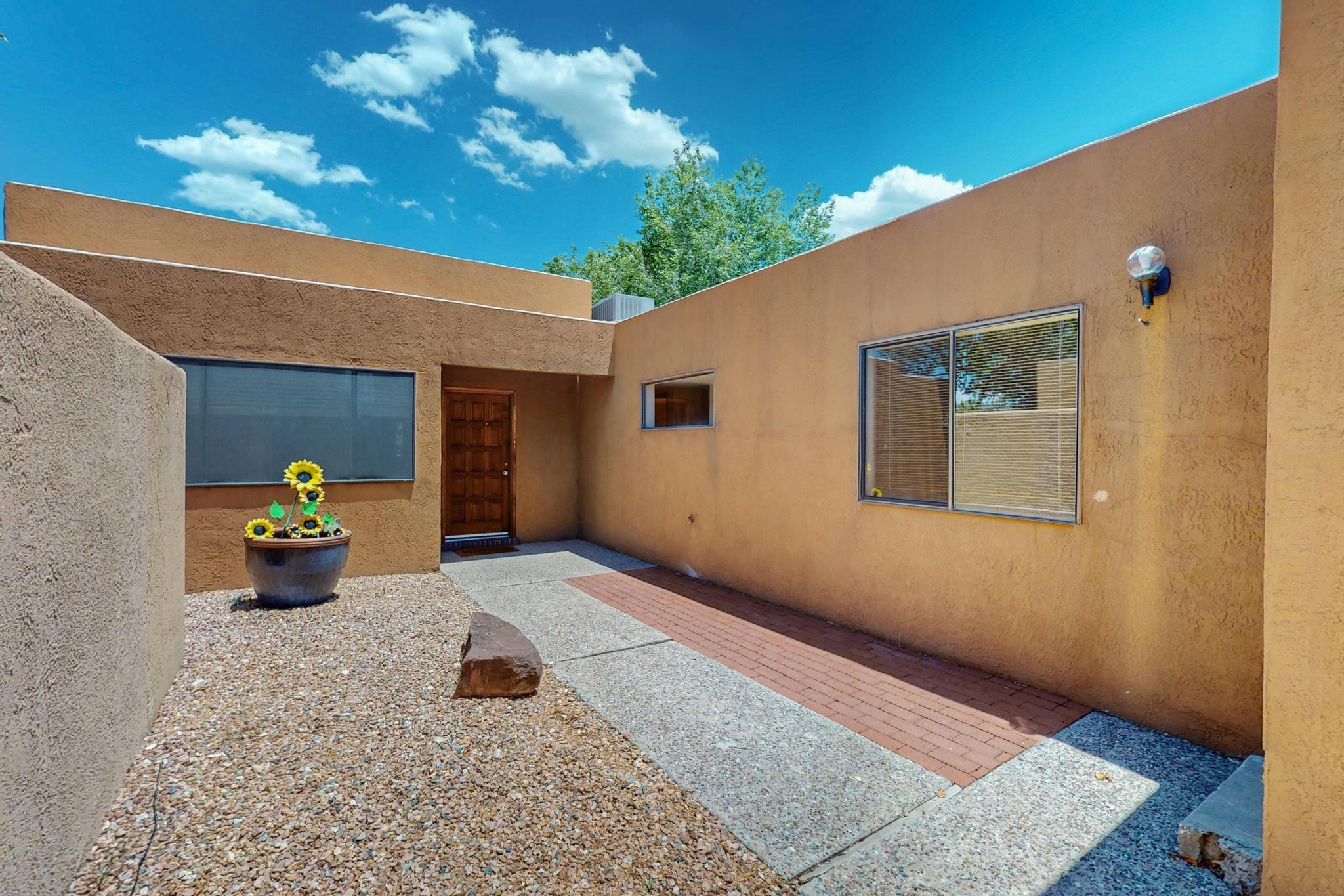 Fantastic patio home located in Sandia Heights. If you've been searching for a one-story property w/incredible views, this may be the one. The home boasts a spacious living area w/ a beautiful tongue & groove ceiling & a welcoming fireplace, perfect for relaxing. The kitchen is bright & has a built-in space that would be ideal for a small kitchen garden. Just off the dining area, you'll find a fenced deck that overlooks the open space, offering a lovely spot to enjoy the surroundings. The primary bedroom features its own en-suite bathroom & two closets, plus a private deck where you can take in the views. Throughout the home, you'll appreciate the natural light provided by the clerestory windows & skylights. Enjoy the southwestern landscape with the foothills outside your front door.