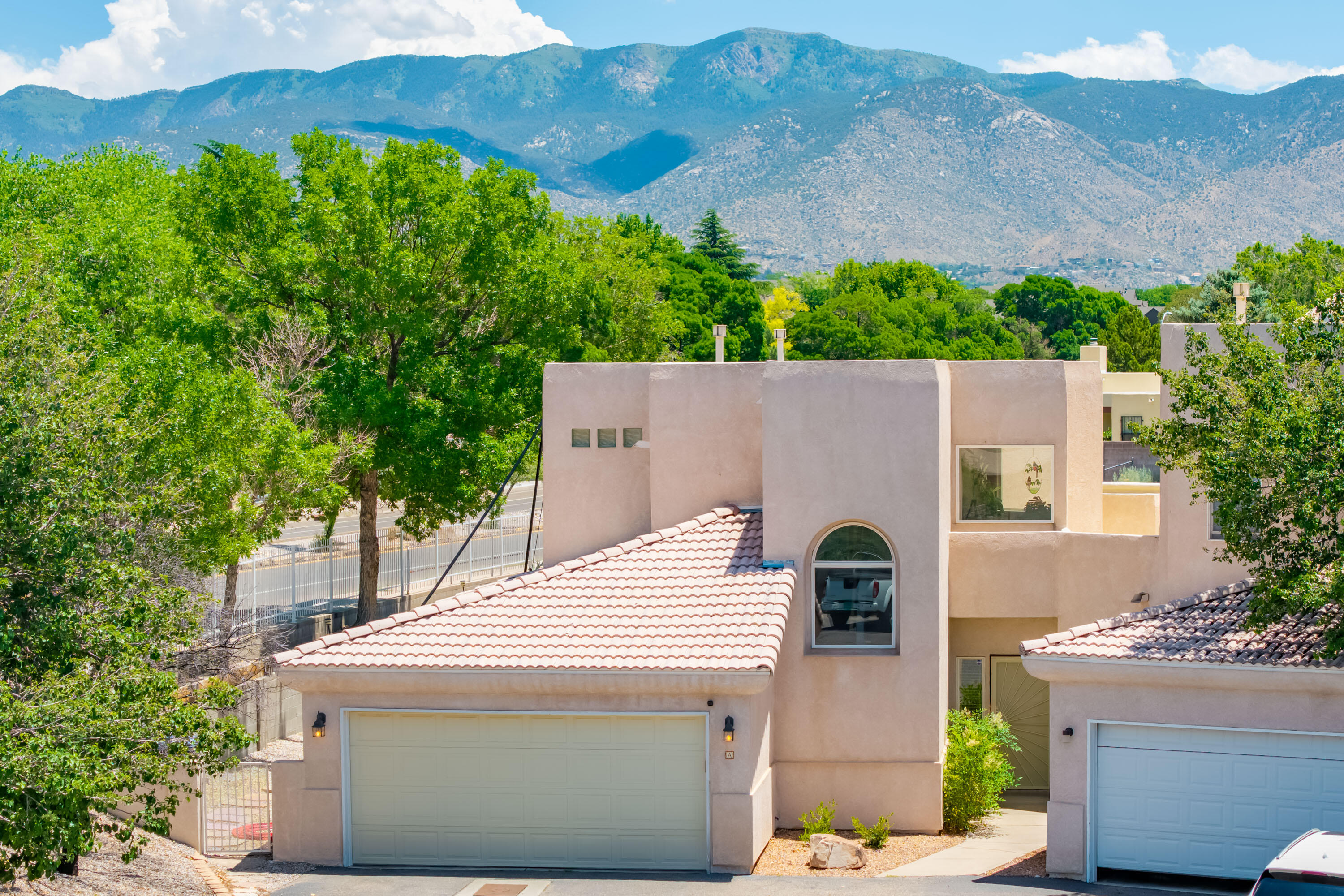 Welcome to this charming NE Heights home! Enjoy spectacular Sandia Mountain views from nearly every window. This prime La Cueva District spot is steps from an awesome park and 5 minutes from shopping/dining. Inside, sun-drenched rooms and cathedral ceilings create an open, airy feel. The bright, updated kitchen with an island and patio access is perfect for gatherings. Imagine easy indoor/outdoor living with the open living/dining area leading to your covered patio and great backyard w/ rose bushes. The spacious downstairs primary suite offers a private escape with patio access, separate vanities, a soaking tub, and a separate shower. Updates include: roof, water heater, furnace, and refrigerated air!