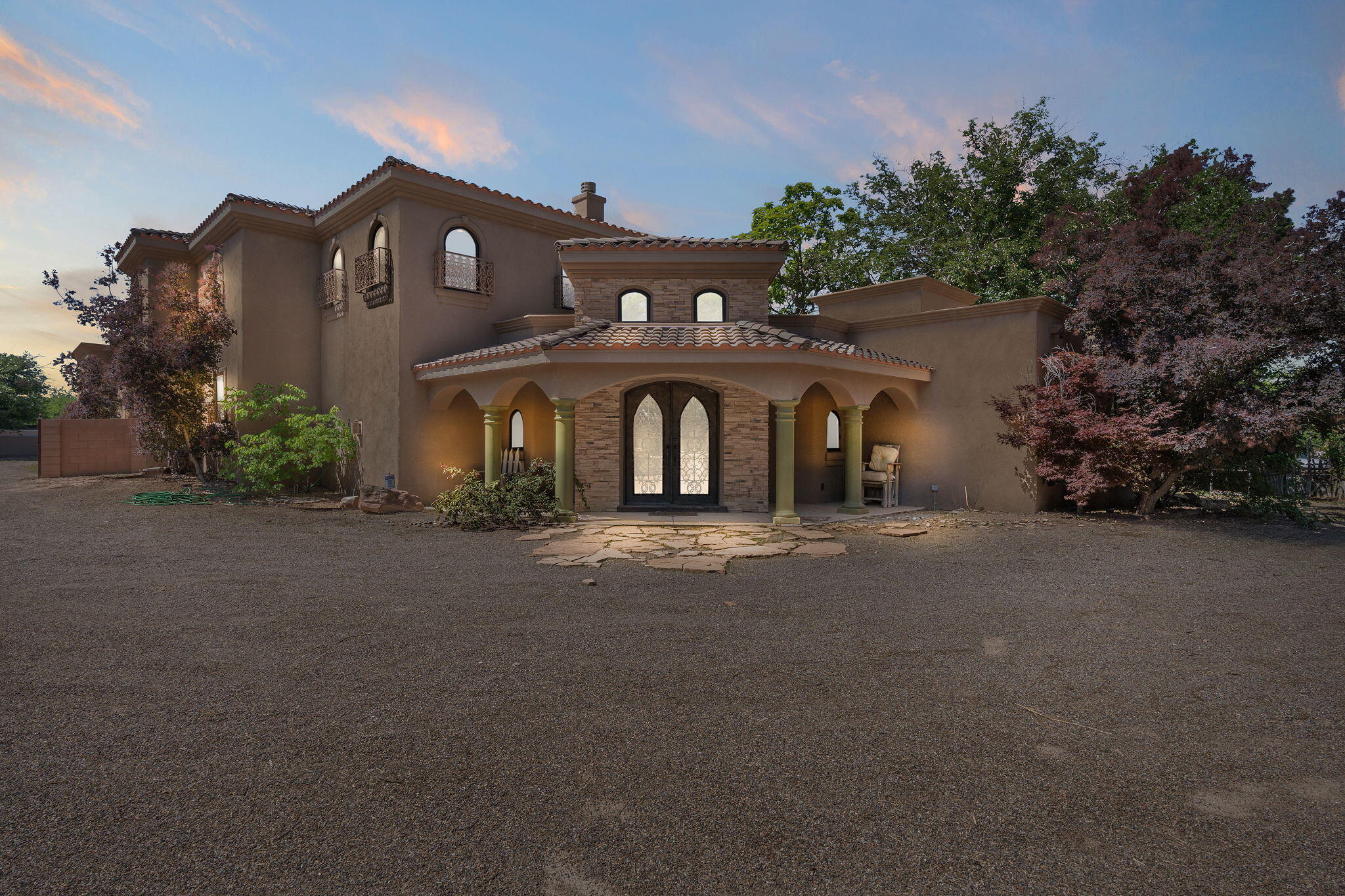 Stunning! Tuscan in sought after Los Ranchos, North Valley neighborhood. With elegant classic exterior lines and rustic earth-tone interiors, arched windows and doors. This home boasts comfort, ease, warmth, and hospitality.  The kitchen has custom cabinetry, granite counter tops, stainless appliances and a center island with counter seating. The primary suite overlooking the rear garden, outdoor balcony, luxurious master bath with a large walk-through shower, jetted tub, double sinks, and oversized walk in closet.  Enjoy the private outdoor entertaining area with a beautiful pool with elevated spa and pond with koi fish.  This home is gated and perfectly placed on 1.13 acres.