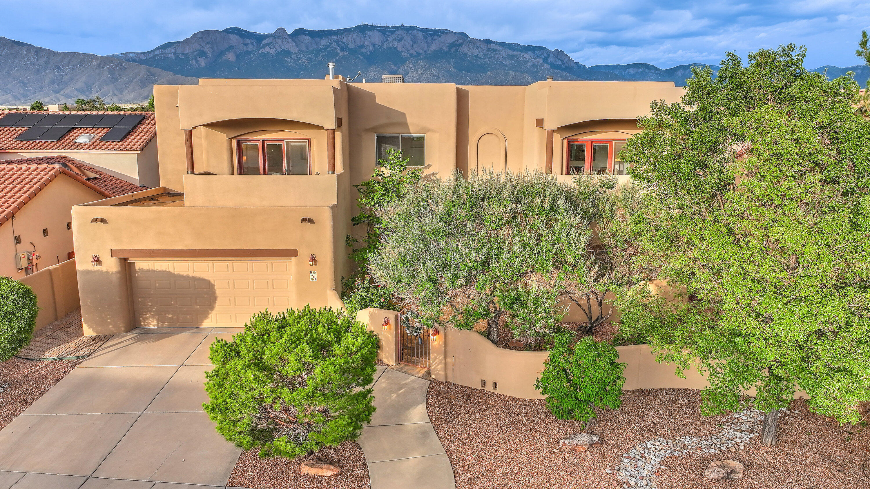 Sandia Mountains, sunsets & city lights in the Desert Ridge gated neighborhood.  This elegant and comfortable home is built by Tiara Homes. The beautiful park-like backyard offers a cozy outdoor fireplace, extended patio, fountain and beautiful landscaping.  Great room with large windows for mountain and backyard views, kiva gas log fireplace and wood beam ceiling.    Downstairs is a guest bedroom with a full bath for multigenerational living or guests. The loft/2nd living area, primary suite and 2 additional bedrooms fill the upstairs.  The balcony off the primary suite is ideal for a quiet evening and mountain views.  Cooking or entertaining is easy in this kitchen with island, solid countertops, wood cabinets, gas cooktop and breakfast nook.  Tandem 3 car garage plus desirable schools.