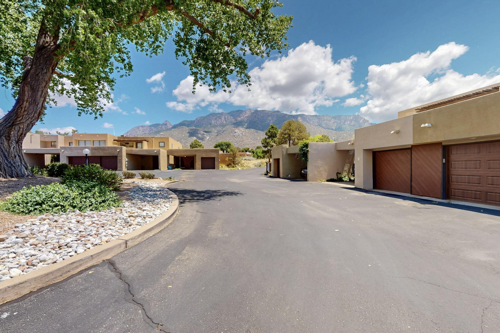 RARE OPPORTUNITY! Single story Townhouse nestled in Sandia Heights. 2-bedroom, 2-bath layout offers low maintenance living. Get ready to sit back & enjoy breathtaking Sandia Mountain VIEWS from your private back courtyard. Hit the foothill trails for a hike or mountain bike ride. Great room with custom wood burning fireplace & more views. Large primary suite has its own door to back patio area. Kitchen nook with partial city views. 1-space carport plus 1 car garage with great storage. End unit so only one shared wall. Refrigerated AC. Shared common area for townhome residents with covered gazebo. This could be your own private escape in the foothills of the Sandias while you're still able to utilize all amenities within the Albuquerque and Santa Fe areas. Find your JOY on Tramway Lane!
