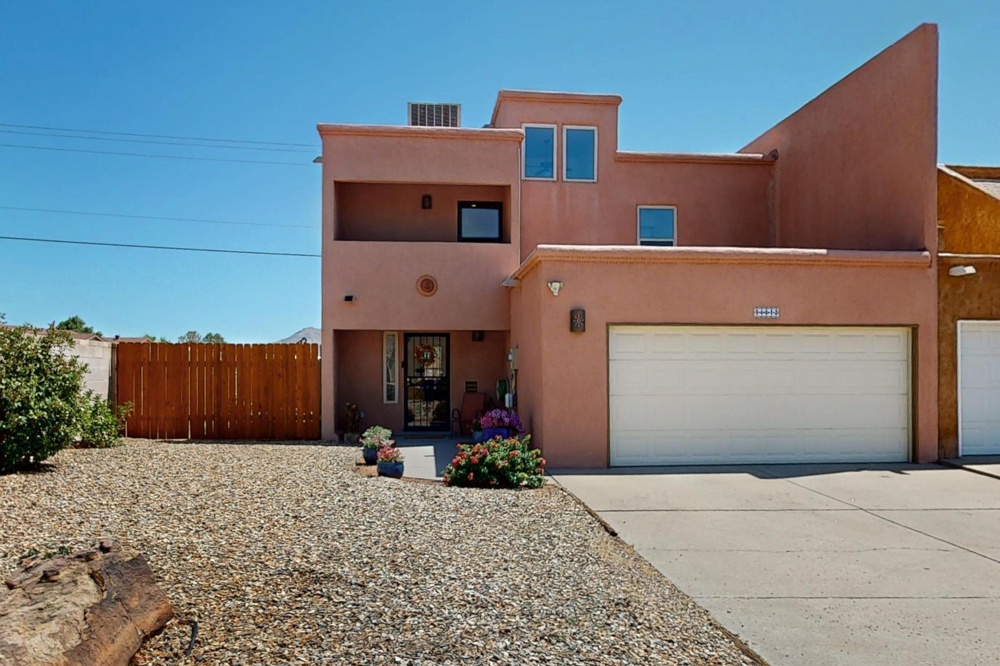 Beautiful Townhome with Mountain Views and Spacious Lot. Nestled in the scenic Albuquerque foothills, this two-story townhome sits on an oversized lot with rare backyard and side access and NO HOA. The main level offers a welcoming living room with a cozy fireplace and vinyl flooring, as well as a dining area that overlooks a private backyard.  The updated kitchen is equipped with stainless steel appliances (all included), granite countertops, subway tile backsplash, a generous walk-in pantry, a convenient half bath, and an adjacent laundry room. Upstairs, the spacious primary suite features a full bathroom and a private balcony with stunning views of the Sandia Mountains. A second bedroom is located near an additional full bath.