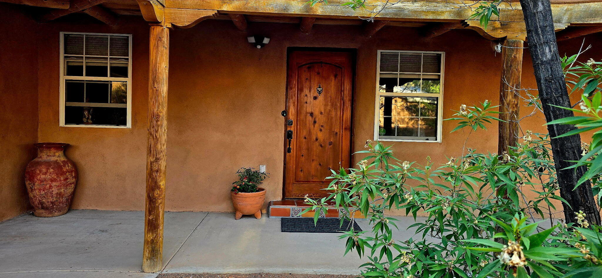 Nestled in the heart of the North Valley, this enchanting 1,900 sq. ft. adobe home on a lush .31-acre lot brims with charm and character. Surrounded by stunning landscaping featuring fruit trees, vibrant roses, and desert willows, the fully fenced property includes a security gate and ample parking space. Perfectly situated next to ditch banks and biking trails, it's an ideal spot for adventures.This 3-bedroom, 2-bath gem boasts authentic viga ceilings, diamond-finished plaster walls, Mexican Saltillo tiles, and original 1959 hardwood floors in the two guest bedrooms. The kitchen shines with custom cabinets and granite countertops. Thick adobe walls ensure cool summers and cozy winters. Enjoy outdoor living with a covered carport, a rear patio perfect for entertaining, and a
