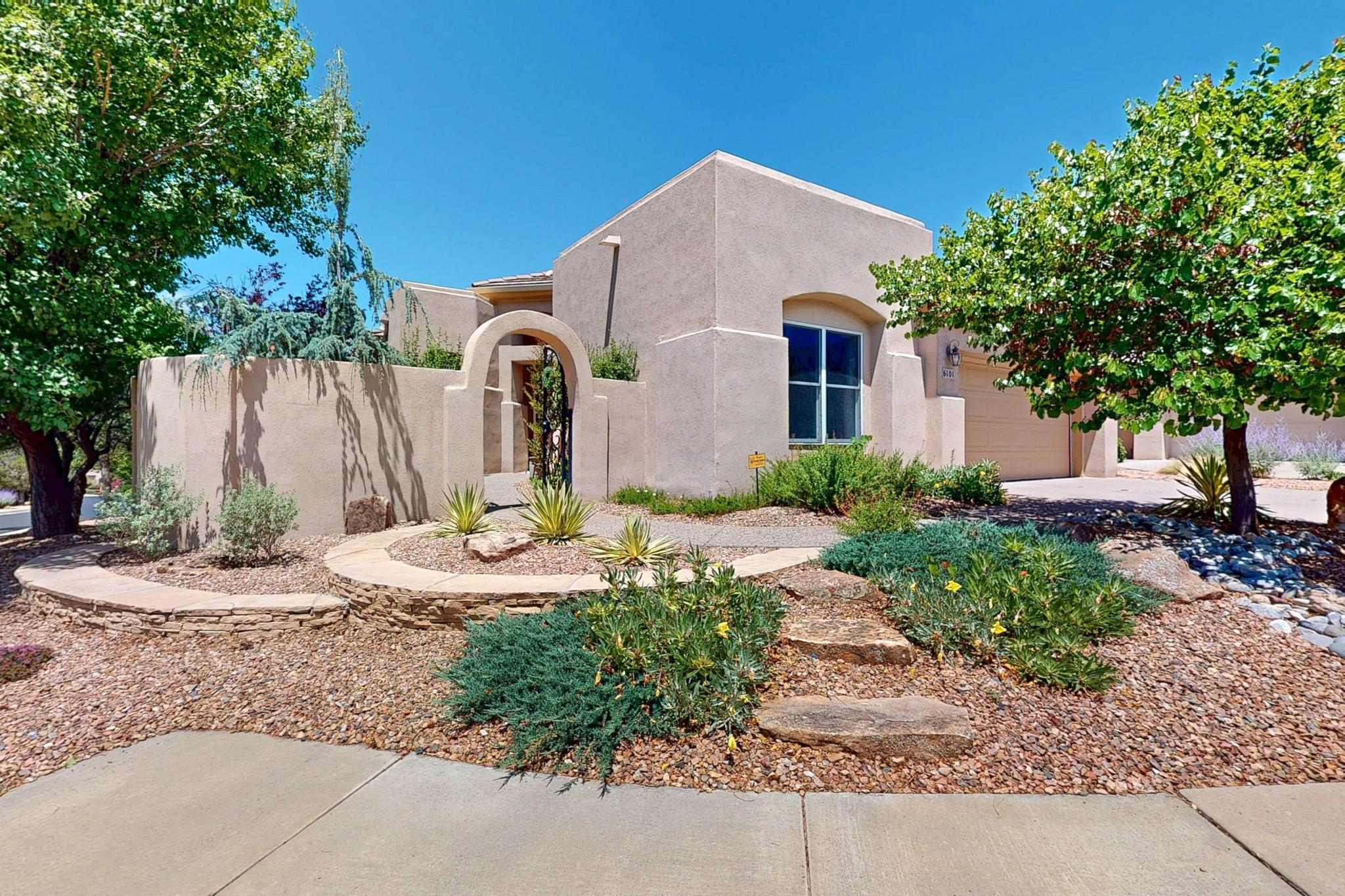 Experience the magic and idyllic Trillium neighborhood in the High Desert community of Albuquerque! Gated, secure, and well-kept, the home is ideally perched right at the entrance, with a neighborhood park a block away.The outdoors are magical, with a walled front courtyard to take in the views of the majestic Sandia Mountains while surrounded by flourishing landscaping. The covered patio off the kitchen is a dream for al fresco dining, and the various rose bushes and mature plants are a magnet for local pollinators. Inside, you'll find a well-kept and well-designed accessible one level floorplan with incredible natural lighting, an oversized chef's kitchen with tons of cabinetry and counter space, a stunning primary suite with separate shower & soaking tub, & much more!