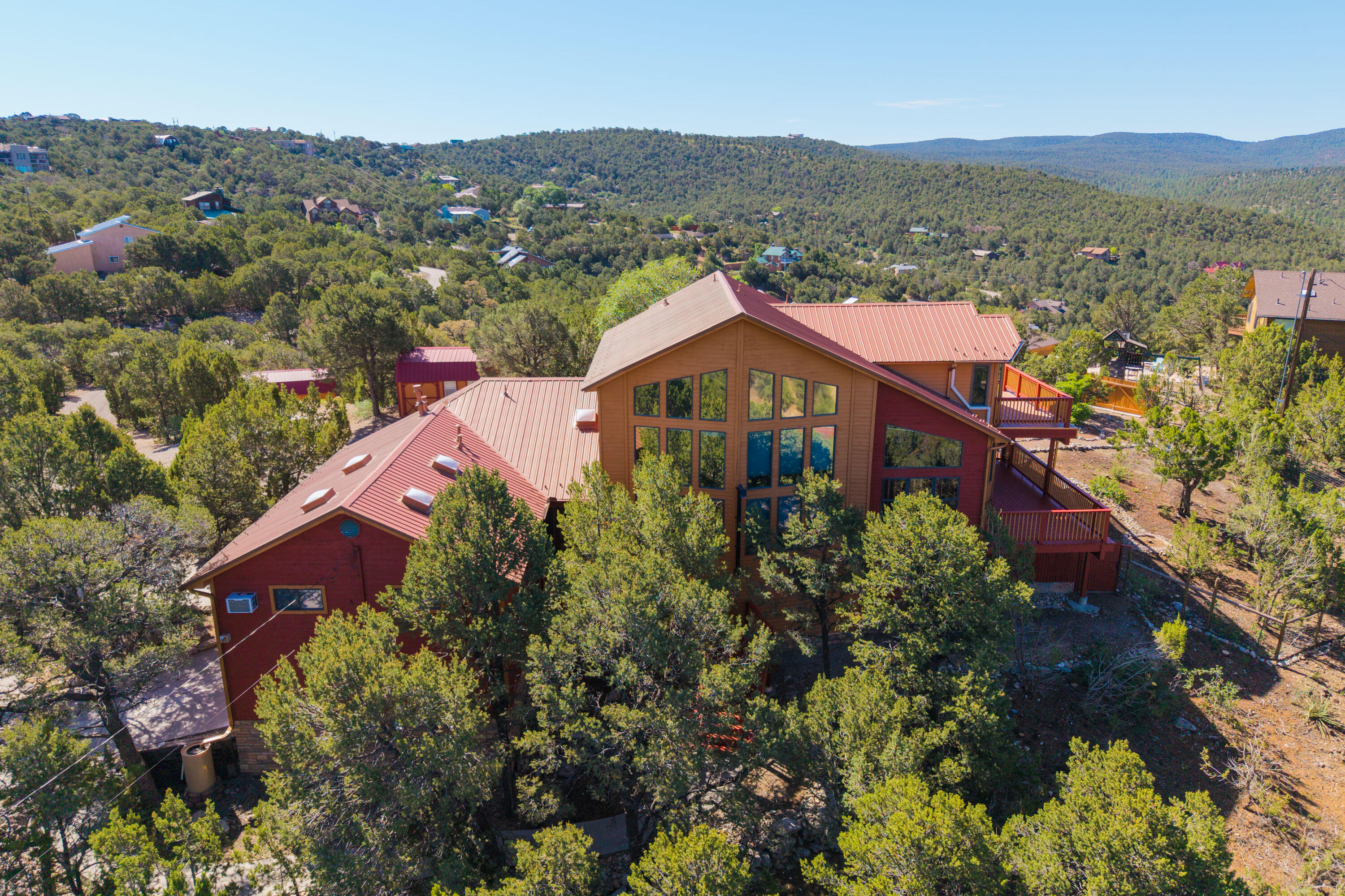 Architecturally stunning mountain retreat! Natural light through the 28 windows w/ views of the east slope of the Sandias & mountains from every room. Lovely updated kitchen-huge island, bar seating, beautiful granite counters, GE Monogram SS appliances including a wine/beverage frig, copper apron farm sink, & open to the dining and living room. Amazing details in the woodwork, hardwood and tile floors, and 24ft ceilings. Primary suite with loft sitting room/office area is dreamy! Spa-like bathroom w/ step-in tiled shower, jetted tub and double vanity plus a closet system in the walk-in closet. Spectacular rebuilt deck with Trex decking and views as far as the eye can see. Covered patio with tongue and groove ceiling, pergola & fenced in yard. Updates to the additional full & half baths.