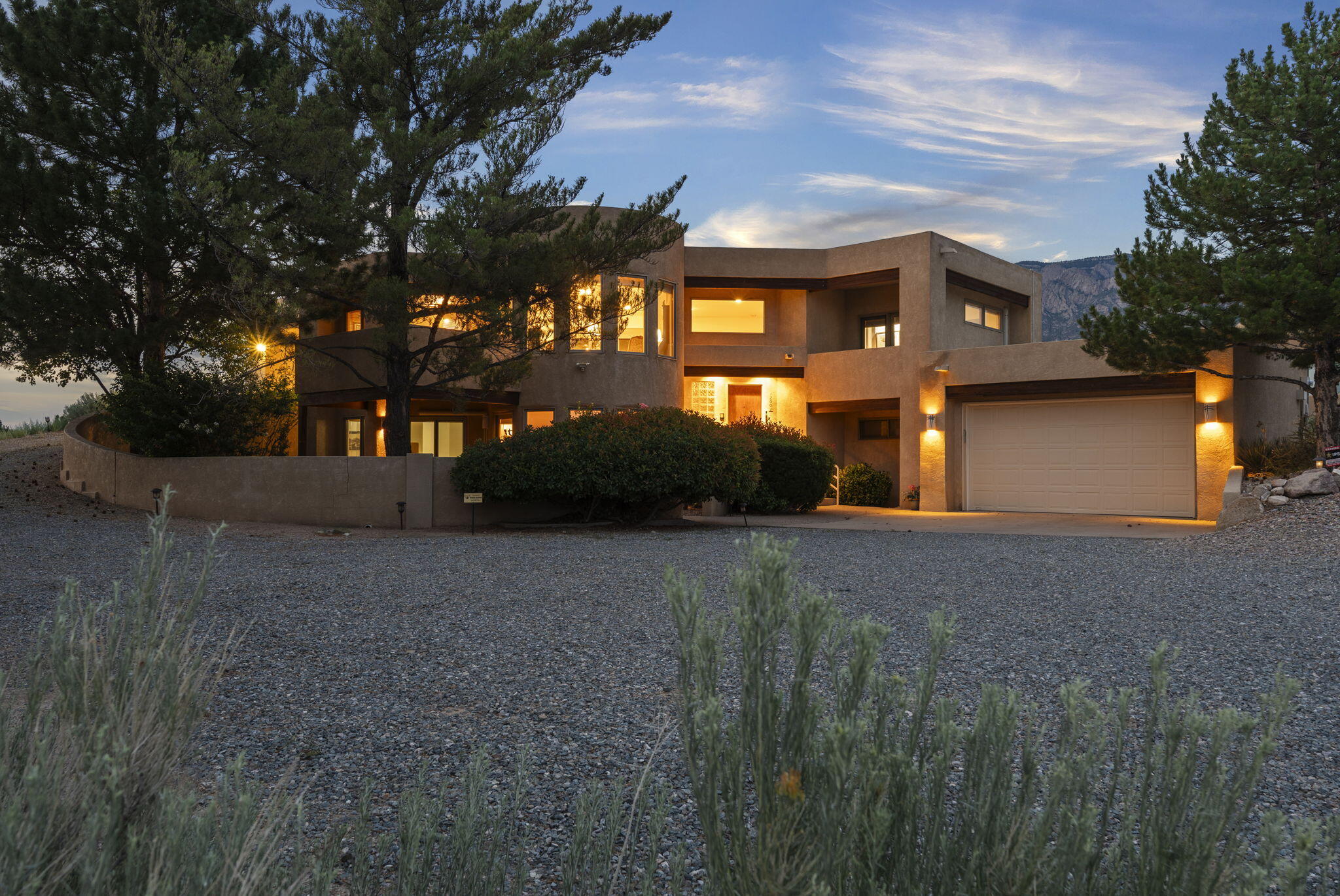 Set on nearly an acre in coveted North Albuquerque Acres, this custom residence blends architectural style with panoramic views of the Sandias and city skyline. Newer TPO roof. Interiors feature hardwood floors, soaring ceilings, skylights, recessed lighting, and ceiling fans, all enhancing the home's natural light and flow. The two-car garage and heated/cooled storage offer flexible space for a gym, workshop, or studio. A private lower level with two bedrooms, its own washer, dryer, and fridge, is ideal for in-law quarters. An upper patio off the kitchen invites al fresco dining with city light views. The backyard is a tranquil escape with covered and open patios, lawn, and mature trees.