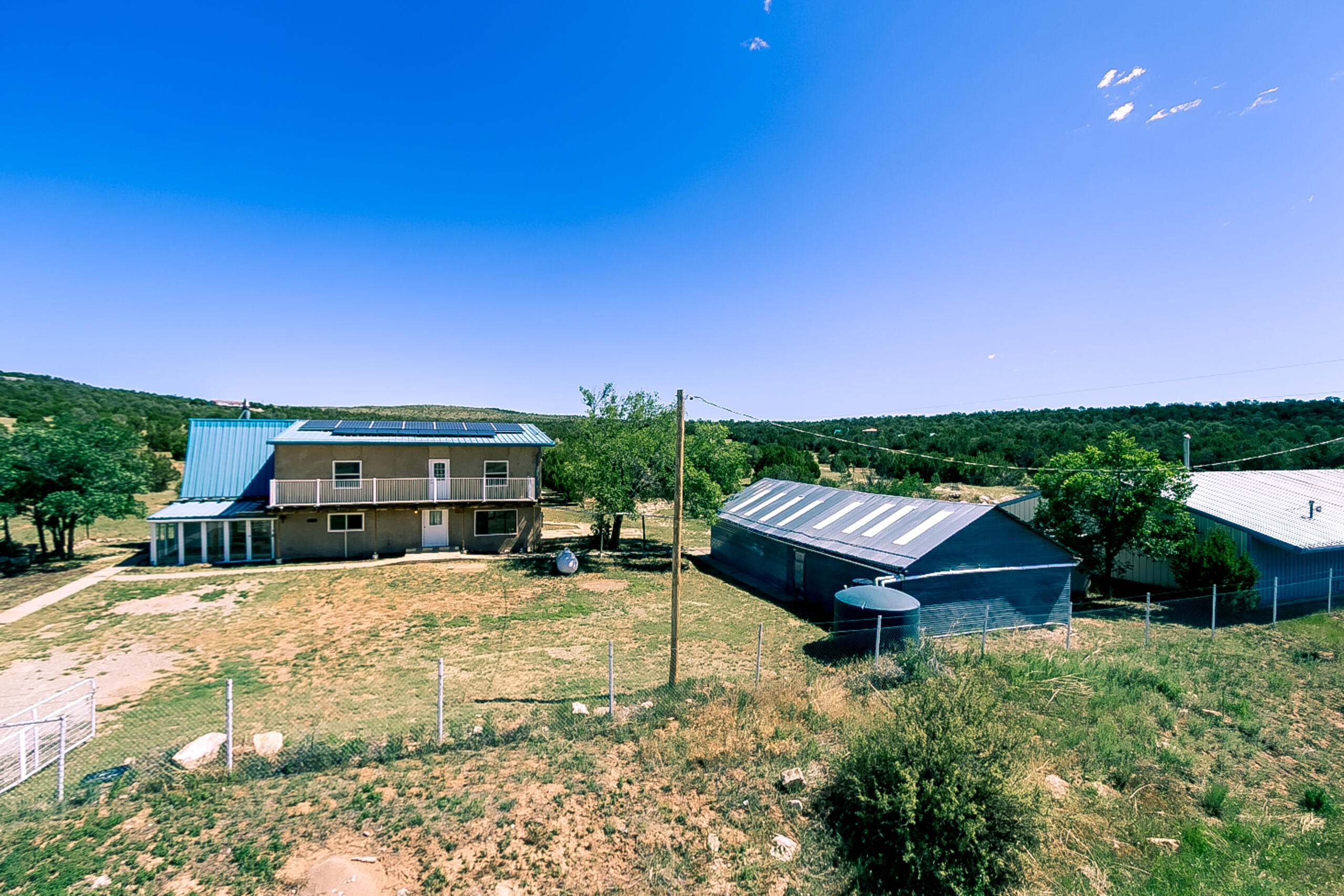 Unique multi-use property on 5.21 acres with meadows, trees, and mountain views. The standout feature is the fully insulated 45' x 80' workshop/garage building, offering approximately 3,225 sq. ft. of space. Constructed with metal beams and high ceilings, this structure includes two office spaces with gas wall heaters, a half bath, loft storage, and capacity for up to 10 vehicles. Ideal for business use, vehicle storage, or hobby space. The 3030 sq. ft. main house features a owned 5.88KW PV solar panel system, a downstairs primary bedroom with two walk-in closets, 3/4 bathroom and private outdoor access. Spacious kitchen with solid wood cabinets, six-burner stainless steel range, large pantry, tons of counter top space and views of the valley and meadows.