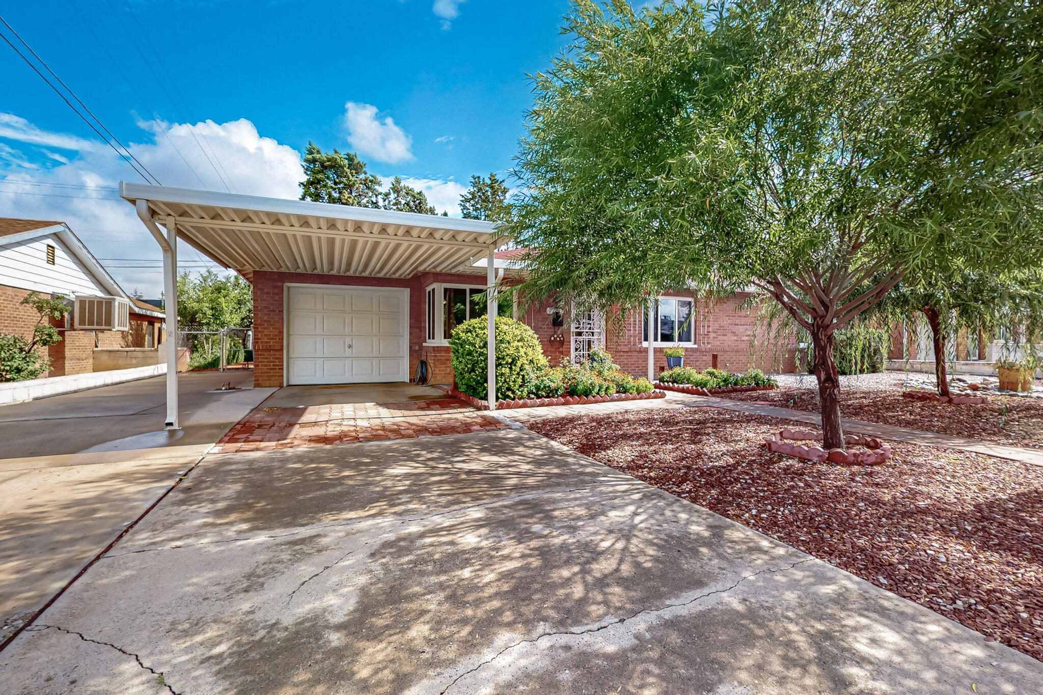 Location! Location! This classic brick home offers timeless charm & an unbeatable location. Situated in the heart of Uptown, you're just blocks away from premier shopping, dining, entertainment, fitness centers, parks, trails & top-rated schools. A gardener's dream, the property boasts one of the best yards in the area-beautifully landscaped with apple & plum trees, Weeping Willows, miniature roses, vines & a variety of vibrant flowers.  It is spacious, & perfect for entertaining or relaxing. Inside, you'll find a warm & inviting layout with three bedrooms, two updated bathrooms (one jack &  jill), an updated kitchen with stainless steel appliances, a dining room, living room & a sunroom. There's also a laundry room with a storage area, a one car finished garage, a carport & RV parking.