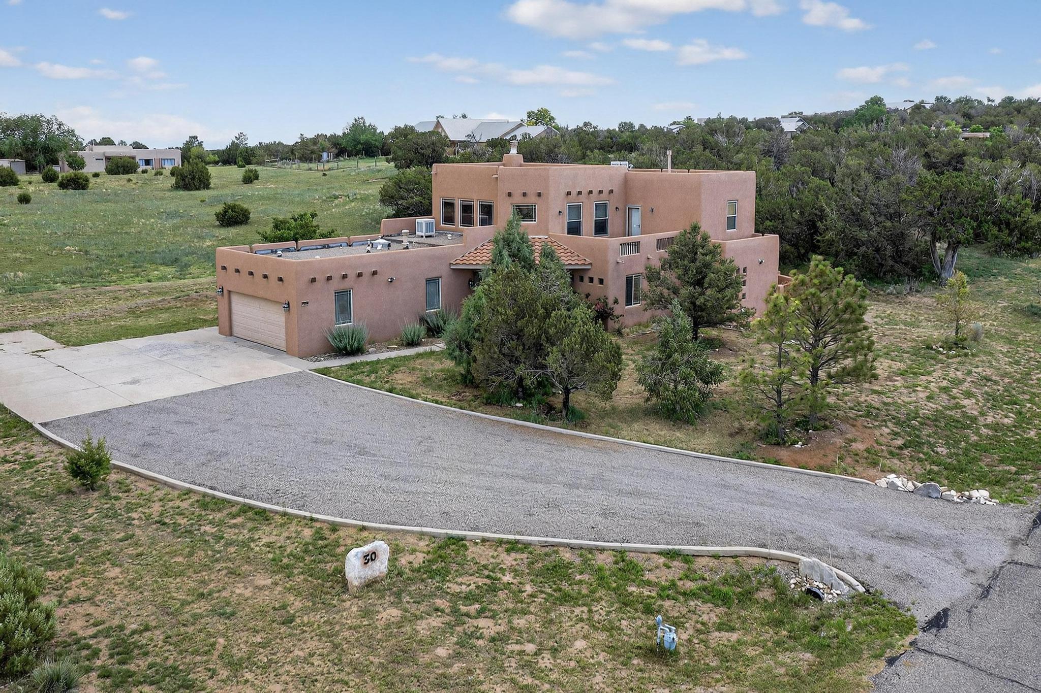 This stunning pueblo-style home sits on 2 beautiful acres in the highly sought-after Tierra Vista Subdivision. The well-thought-out floor plan has the primary suite on the main level of the home, complete with a large walk-in closet, garden tub, and a separate walk-in shower. The open, airy living area boasts high ceilings and several large windows that allow in plenty of natural light. Sit and relax on the upper-level deck, which offers amazing views. The two fireplaces, wood accents, and a lovely lath and viga ceiling give this home so much appeal! The well-manicured backyard and patio area are complete with apple and cherry trees. Community water system, natural gas, a reverse osmosis and softener system, and so much more!