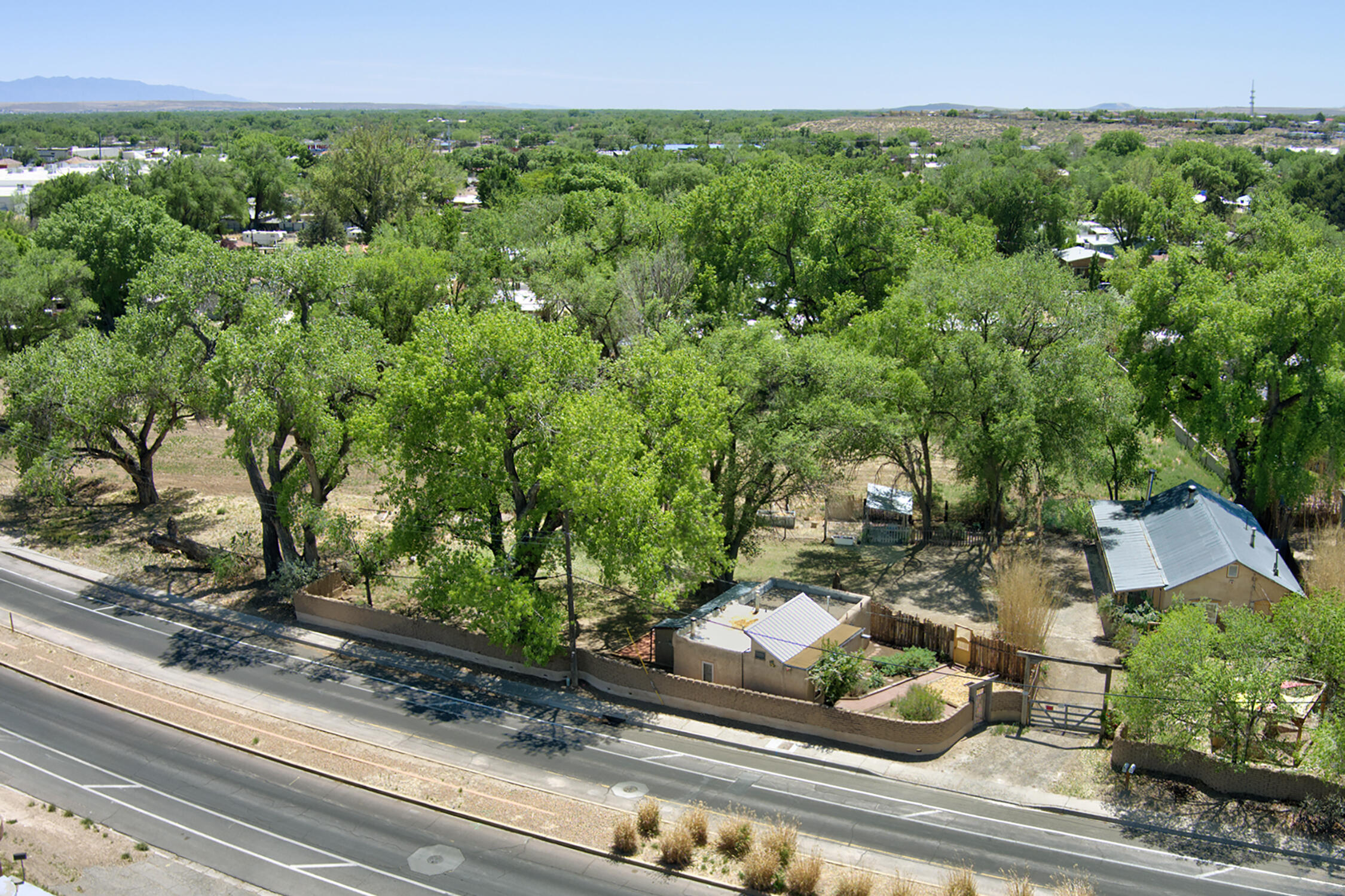 Now available separately, also as a package for the whole compound: MLS 1083024. The 2-bed/2-bath house is on .19 acre; the compound is bordered on one side by a sturdy adobe wall, and verdant agricultural land on the other, and is just half a mile from Rio Grande Bosque hiking trails. Truly a world away, authentic valley living located just west of downtown/old town. Crisp fresh paint throughout showcases the beautiful construction, wood beamed ceilings, and brick floors. With a wraparound porch, and two kiva fireplaces, you can't hear any traffic noise from inside. Truly special and loved.