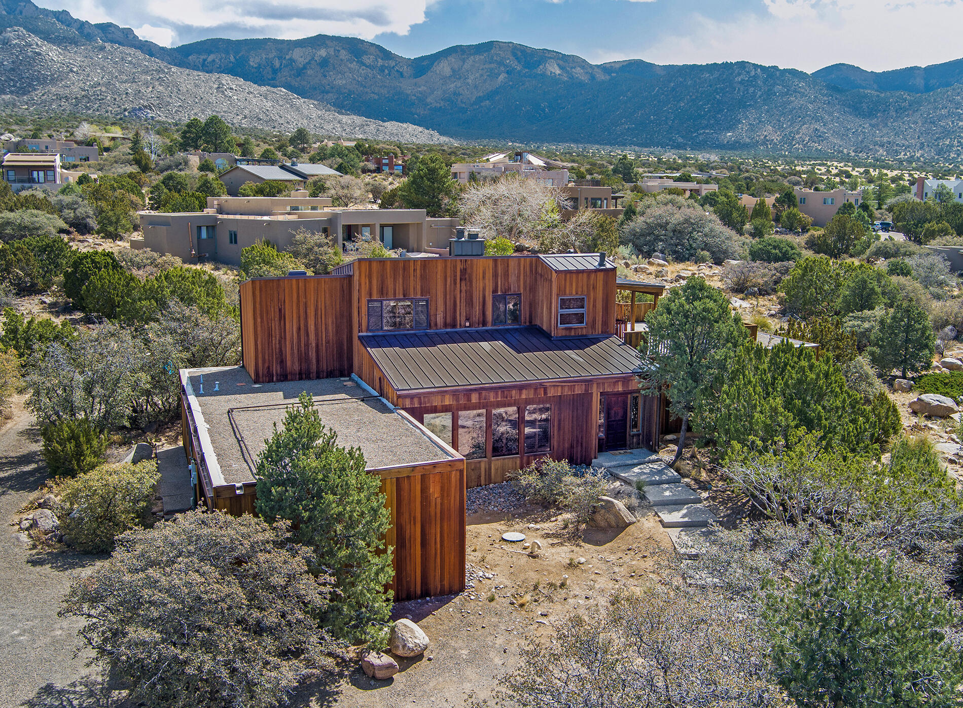 Sandia Heights custom home w/ sensational 360-degree VIEWS & a sense of privacy on incredible 3/4 acre lot. Warm and inviting w/ beautiful redwood siding, raised ceilings, Saltillo tiles, and premium wood shutters. HUGE PRIMARY SUITE upstairs w/ views, fireplace, bathroom suite, large walk-in closet & connects to enormous deck with amazing views of mtns/valley. Bright, kitchen/dining, granite counters, maple cabinetry, counter seating, lots of storage, panoramic mountain VIEWS. Three more spacious bedrooms on main floor, plus flex room or office. Spa suite w/ hot tub, sauna, bathroom. NEW metal roof & NEW gutters (2025), re-finished floor ducts (2025), NEW 50 gal water heater (2025), new garage roof (2019), NEW upgraded septic (2022). Extended garage. Refrigerated air, 2 newer units.