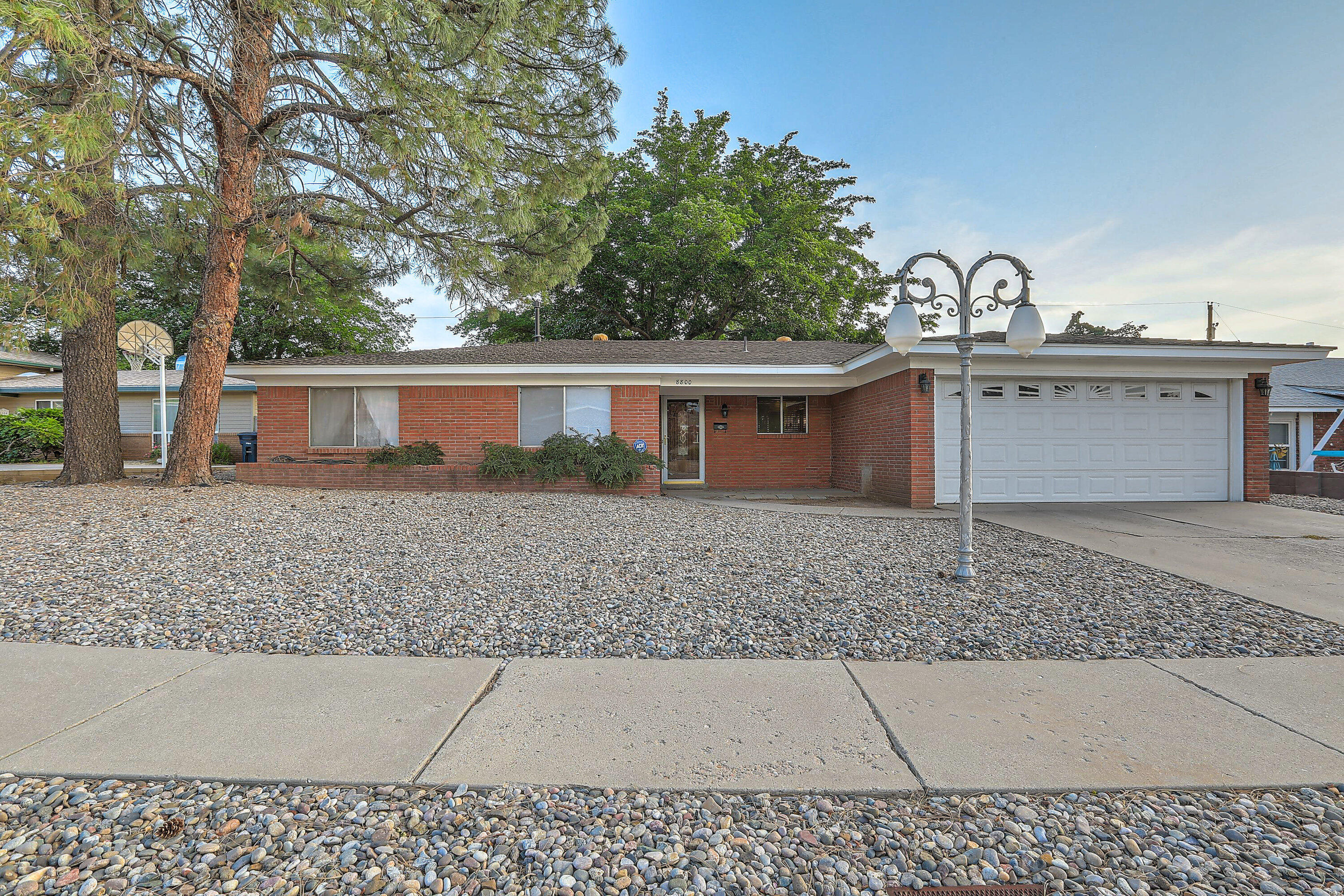 Lovingly cared for, solid brick home in a prime location in the NE Heights.  Easy access to I-40, Uptown, services, parks & restaurants.  Combination living and dining room next to a spacious kitchen with ample countertops & cabinet space.  Large family room with gas fireplace opens to back yard with an open patio, mature shade tree & lawn.  Primary bedroom suite features a remodeled shower & tile flooring in 2021, double closets & built-ins.. All bedrooms and family room have newer carpet.  Convenient half bath next to the laundry room.  2-car finished garage features attic, wall of cabinets & countertops plus a large pantry.  All appliances stay including refrigerator, washer and dryer.