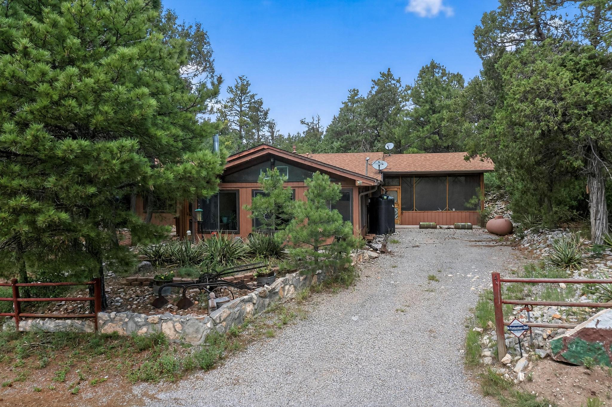 Gorgeous mountain retreat tucked away on 2 wooded and secluded acres  in Albuquerque's beautiful East Mountain area. 2381 SF, 3 BR, 1 3/4 bath single-level, ranch-style home.  Spacious great room with a wood-burning stove. Beautiful kitchen with custom cabinets, island and bar that opens to great room. All appliances convey.  Primary suite features large walk-in closet. Bonus great room is drenched with light. Could be a second living area, office or art studio.The homes outdoor spaces are serene and inviting and include a water feature , firepit area, hot tub, and a spacious back deck and large screened-in bonus room with a brick floor for outdoor living and entertaining.