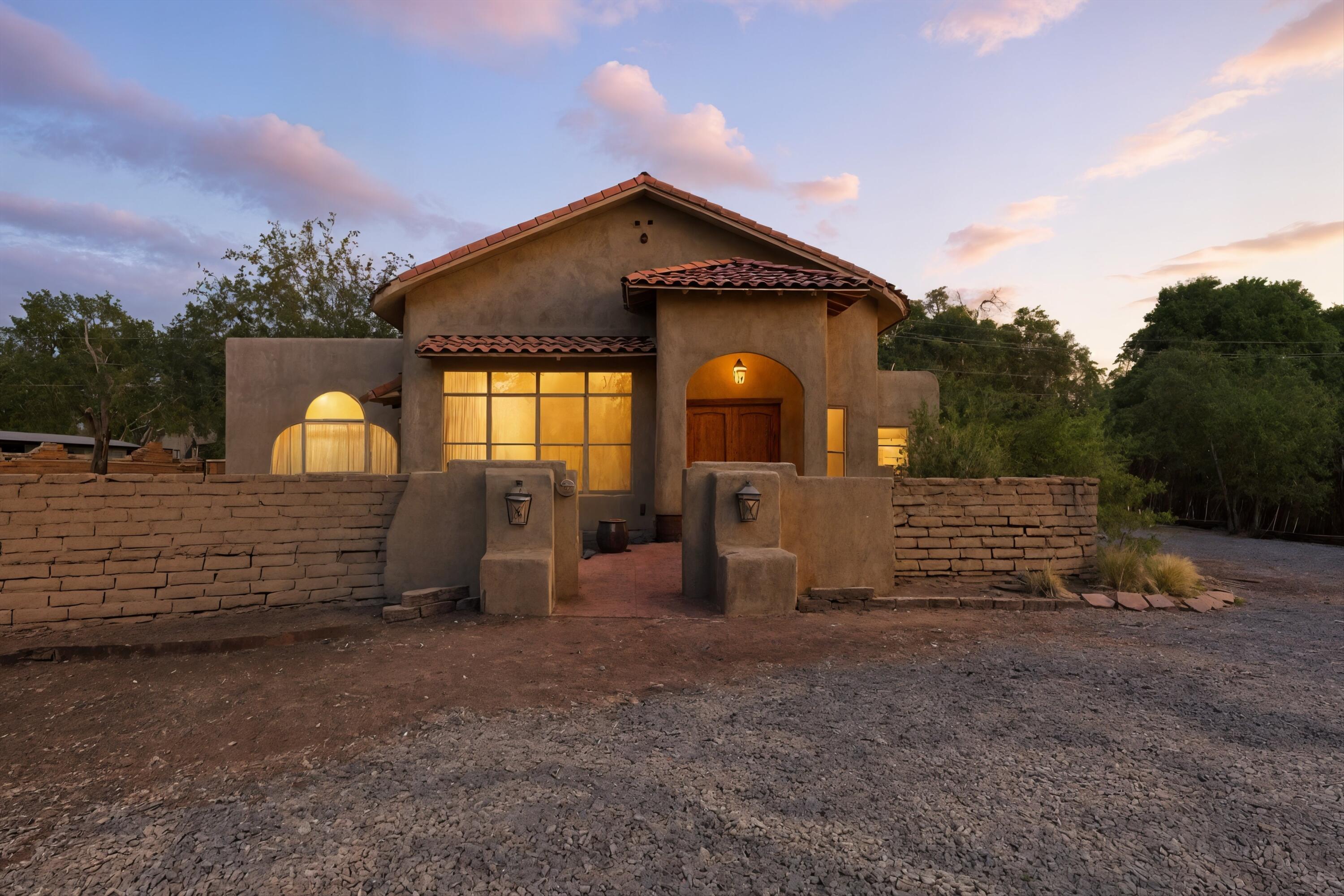 This is a rare opportunity to own a lush one-acre property in highly desirable East Corrales, complete with valuable water rights and irrigation access. The grounds are truly special, featuring mature shade trees, fruit-bearing pear, apple, plum, mulberry, and peach trees, a horse barn, and direct access to the Rio Grande Bosque trails, just a short five-minute walk away. Whether you're envisioning a small orchard, vineyard, or peaceful retreat with farm animals, this fully fenced property offers privacy, beauty, and endless possibilities.The home itself blends historic charm with thoughtful updates. Constructed with original adobe, this home features cathedral ceilings, wood and tile floors (no carpet), and two fireplaces, one of which is a traditional adobe fireplace that adds