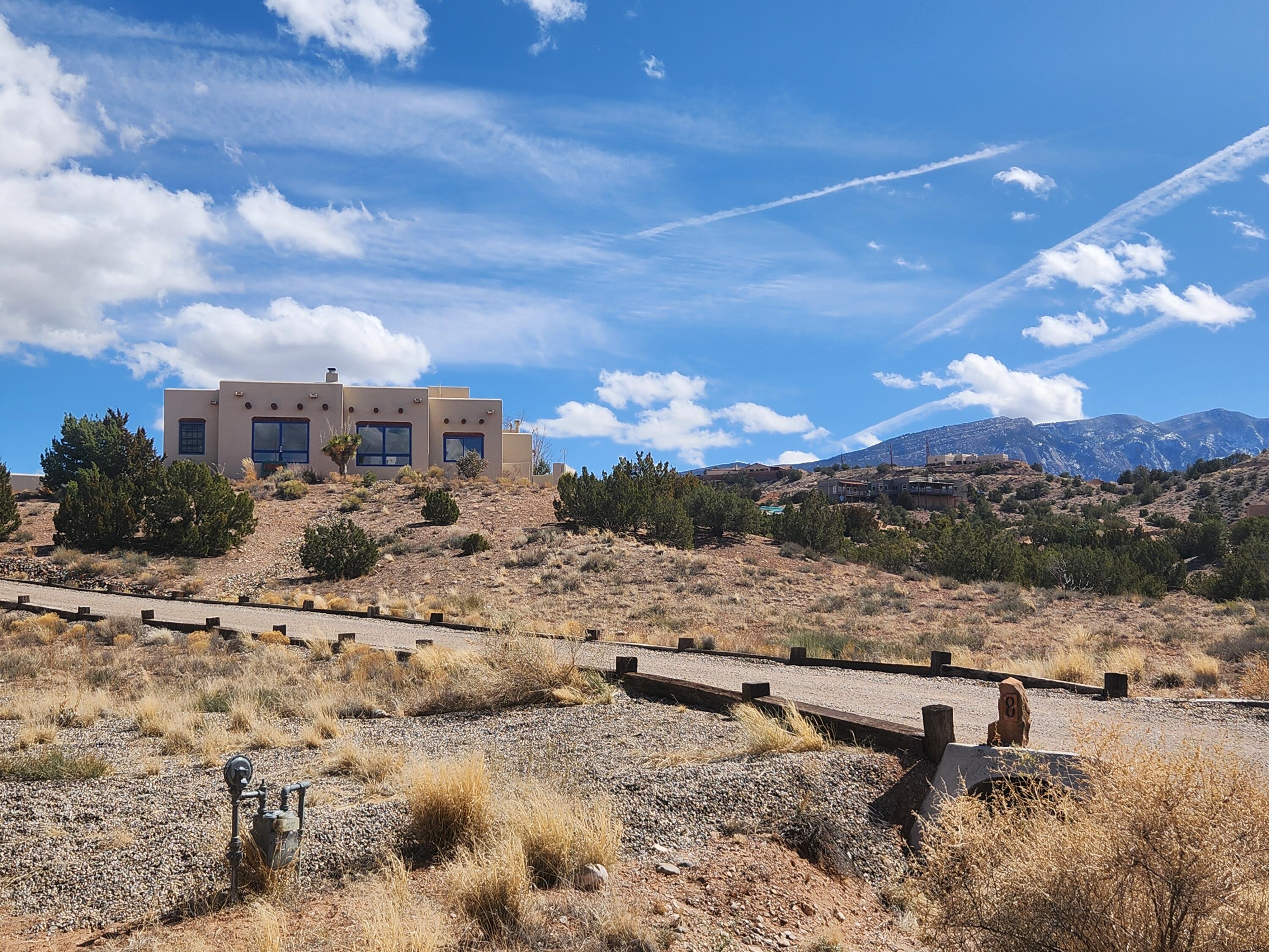 3 BEDROOMS + OFFICE + STUDIO ON 6 ACRES! $810,000. This very private home boasts spectacular views of the mesas from the living, kitchen and dining rooms, as well as views of the Sandias from the primary suite! The 6 acres is surveyed as 2 lots, so you have tons of privacy & you could build another home. Dynamic floor plan with separate studio (or media room...) accessed through the private enclosed courtyard! Remodeled kitchen has new cabinets, stainless steel appliances & granite counters. Oversize (1315 sf) garage can fit 2 cars + your RV and still has space for workshop & storage. Recent TPO roof, water heater & cooling. Pueblo style with beams (vigas) ceilings, kiva fireplace, nichos, Mexican tile floors & arched hallway. On community water. The closest neighbors are over 200' away!