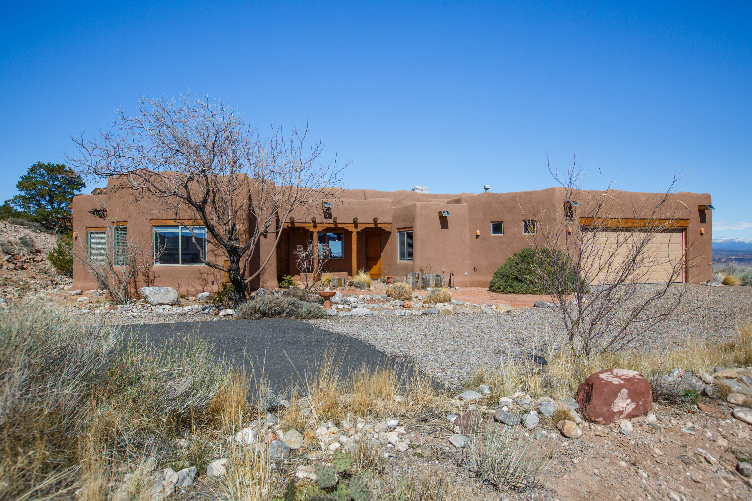 Looking for the quintessential Placitas sanctuary? This custom home is where luxury meets tranquility. Enveloped by the hills of Overlook, this property offers timeless vistas. Stepping into the home, you are greeted by authentic adobe walls, rustic saltillo tile, a lovely kiva fireplace and expansive views of the Jemez Mountains, Cabezon Peak, and more. The primary suite features a beautifully tiled bathroom and an exterior door leading out to the western patio. Down the hall you will find a third bedroom with its own entrance perfect for multigenerational living. This gem is positioned for seclusion yet is 10 mins from I-25. Outdoor enthusiasts will love the nearby Placitas 10K loop trailhead, a haven for exploring the landscape. You do not want to miss this one. Come see it today!