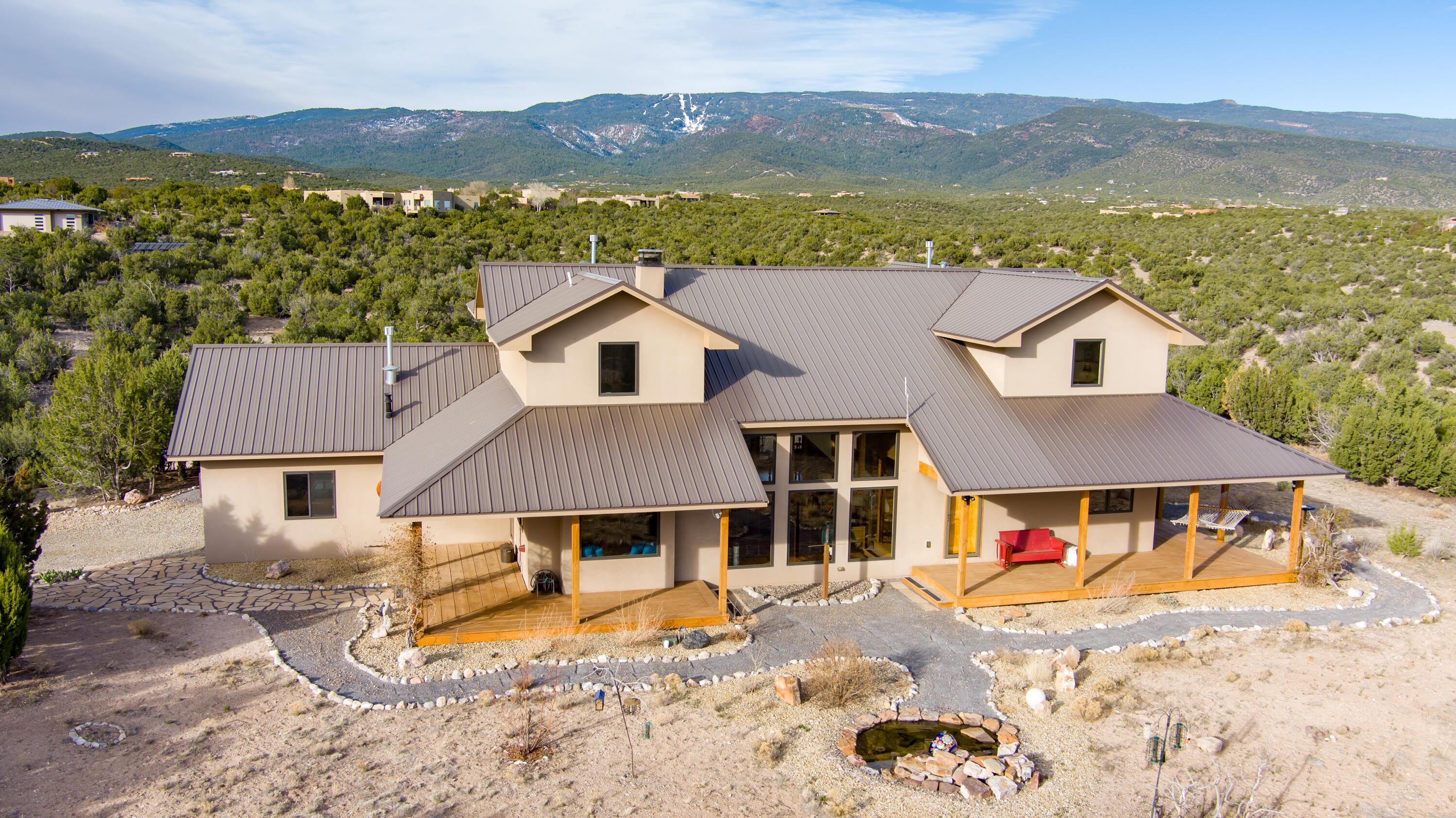 Welcome to your dream Northern New Mexico Style home on 10+acres of pristine land! This fully-integrated smart home features a wrap-around porch where you can enjoy the breathtaking views of the surrounding mountains and landscape. Step inside to an open floor plan with beamed ceilings and stunning Alabama poplar wood floors that create a warm and inviting atmosphere. The living room boasts a locally quarried 2-way stone fireplace and oversized windows. The updated gourmet kitchen has a copper farmhouse sink, granite countertops, top-of-the-line appliances, customized cabinets with special pull-out drawers. 4 bedrooms with the primary on the main floor and the loft/gym has a built-in Murphy bed. Pella wood frame windows. Outside you'll... (con't)