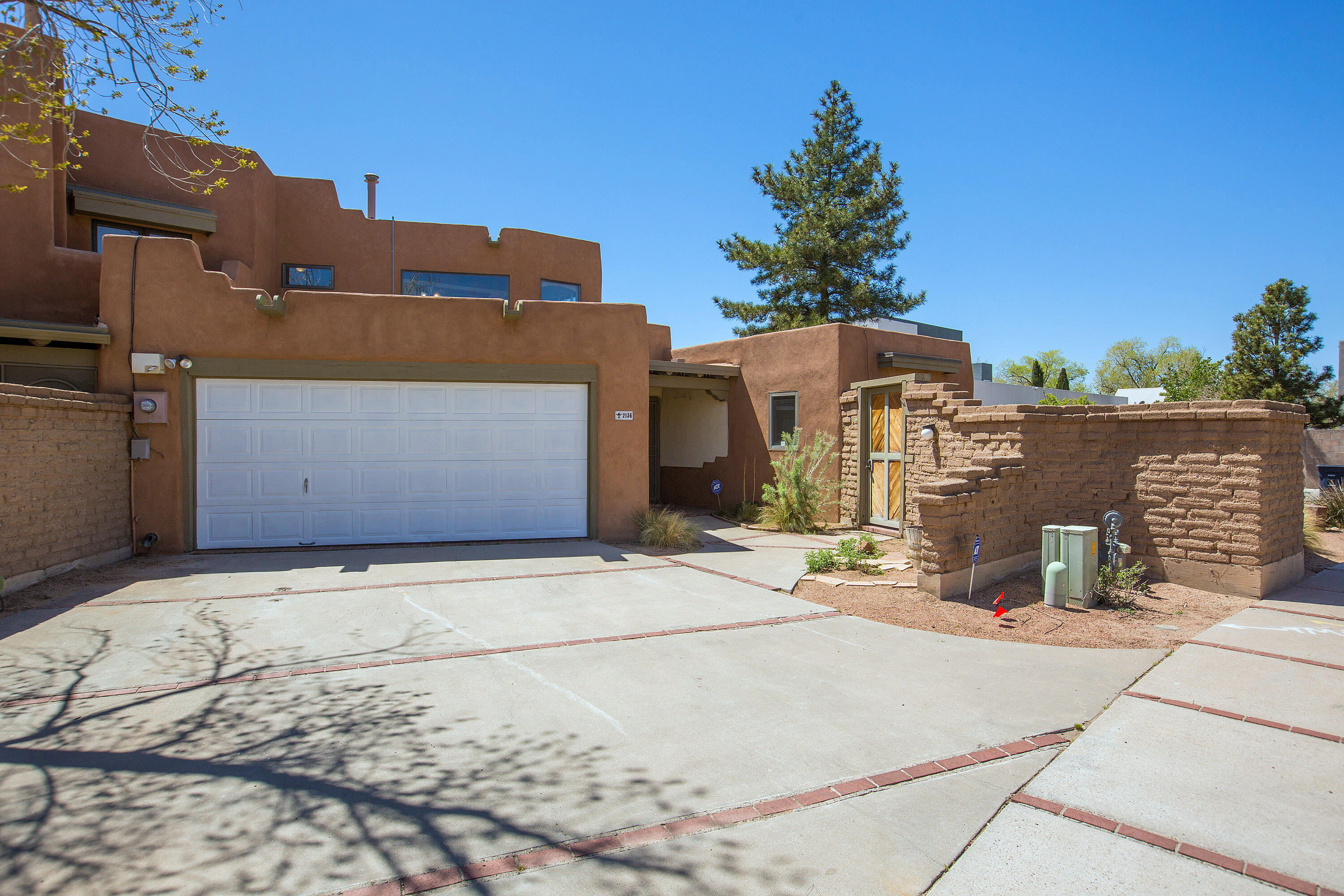 Fabulous Custom Pueblo-Style Townhome in desirable North Valley! Brick floors, authentic kiva fireplace, wood ceilings are Southwest Signatures to this amazing Adobe home! There are 3 bedrooms, 2 bathrooms and a 2-car garage plus refrigerated air! The spacious owner's suite is private and upstairs. Built-in bookshelves and wood beam ceilings plus a Trobe wall with exposed Adobe blocks invite you to stay!  Covered patio and private back yard lend to the North Valley vibe. The private courtyard off the third bedroom provides a tranquil morning coffee spot. Excellent proximity to Bosque trails, Flying Star, The Range Cafe and Las Montanitas Co-Op plus easy access to I-40, Coffee Shops, Downtown, Old Town, Sawmill District, shopping, medical care and more!