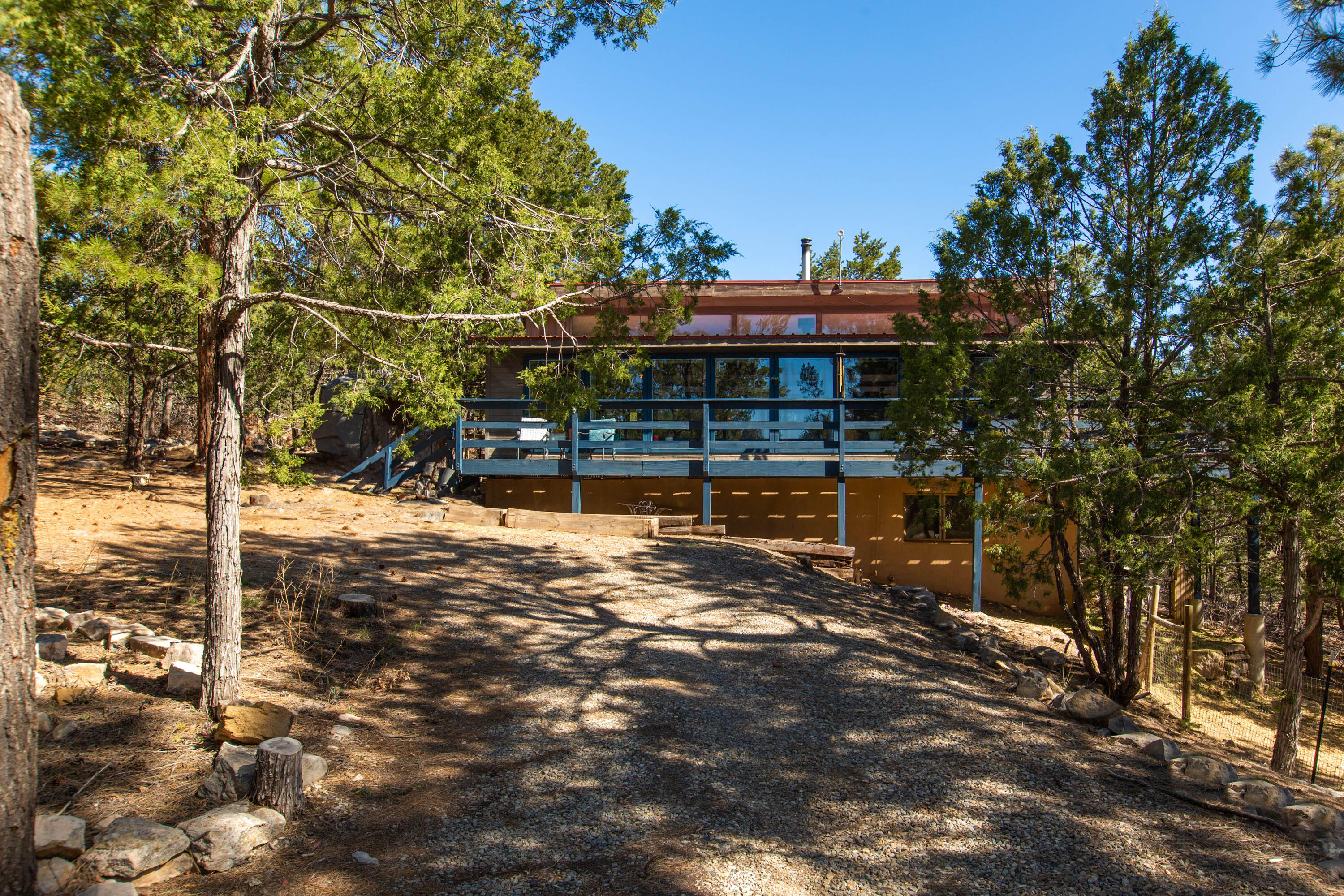 This private mountain retreat is located in Tijeras, just far enough from the city, but close enough to enjoy convenience. This charming and eclectic home features 2 living areas, a cozy wood burning stove, and unique fireplace to enjoy on winter days! The .5 acre lot is ready for your furry or feathery friends, with a  chicken coop ready for your flock! Passive solar, charming brick floors and walls, high ceilings, a large deck to enjoy the mountain air, and light and cheery home. Property requires hauled water, on owned propane, and septic. Contact your favorite realtor for a showing today!