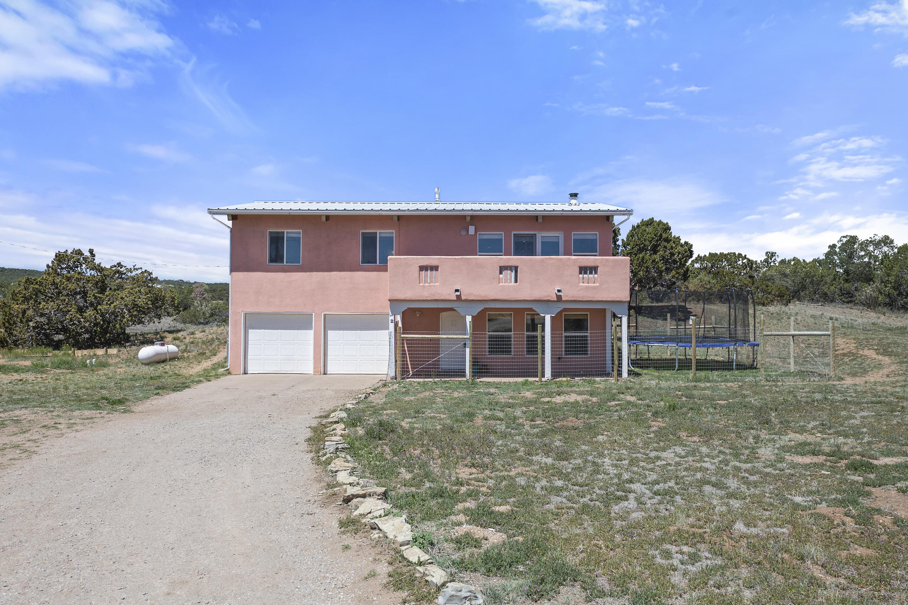 Welcome to your serene sanctuary in Edgewood, NM! This 2 story home on 2 acres offers a peaceful retreat with 3 beds, 3 baths, and a versatile flex room in the garage. Delight in the views of the sunrise from the front balcony, and sunset from the back deck and sunroom. Recent upgrades including refrigerated air and a new furnace ensure year-round comfort and efficiency. The fully fenced yard boasts 2 separate areas perfect for pets or potential farming endeavors with a convenient water line already in place. Enjoy the charm of hardwood floors, wood ceilings, and beams throughout, creating an inviting ambiance. Additional features include a stainless steel kitchen appliance package, paved roads leading to the property, radon mitigation system, spacious shed, & automatic gate.