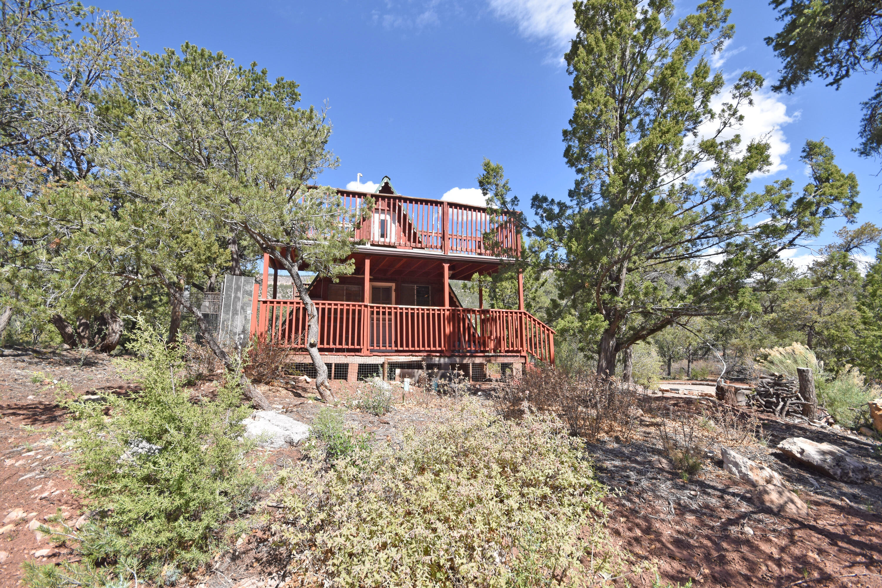 Talk about the perfect getaway at a great price! This cozy A-Frame nestled on a wooded lot in Area 2, just north of Jemez Springs, is a diamond in the rough with endless possibilities! Great potential for an investment property or add your own finishing touches and make it your go-to for weekend retreats. Double decker decks on the east and west gives you plenty of space to enjoy the views of the spectacular soaring mesa walls! There is a space for sleeping quarters downstairs or to use as sitting area. Functional Galley kitchen, a wood burning stove to keep things cozy in the living area, as well as a mini split system. Loft upstairs to use as a bedroom, or as a spot for guests. Bring vision and a hammer, the sky is the limit with this charmer!