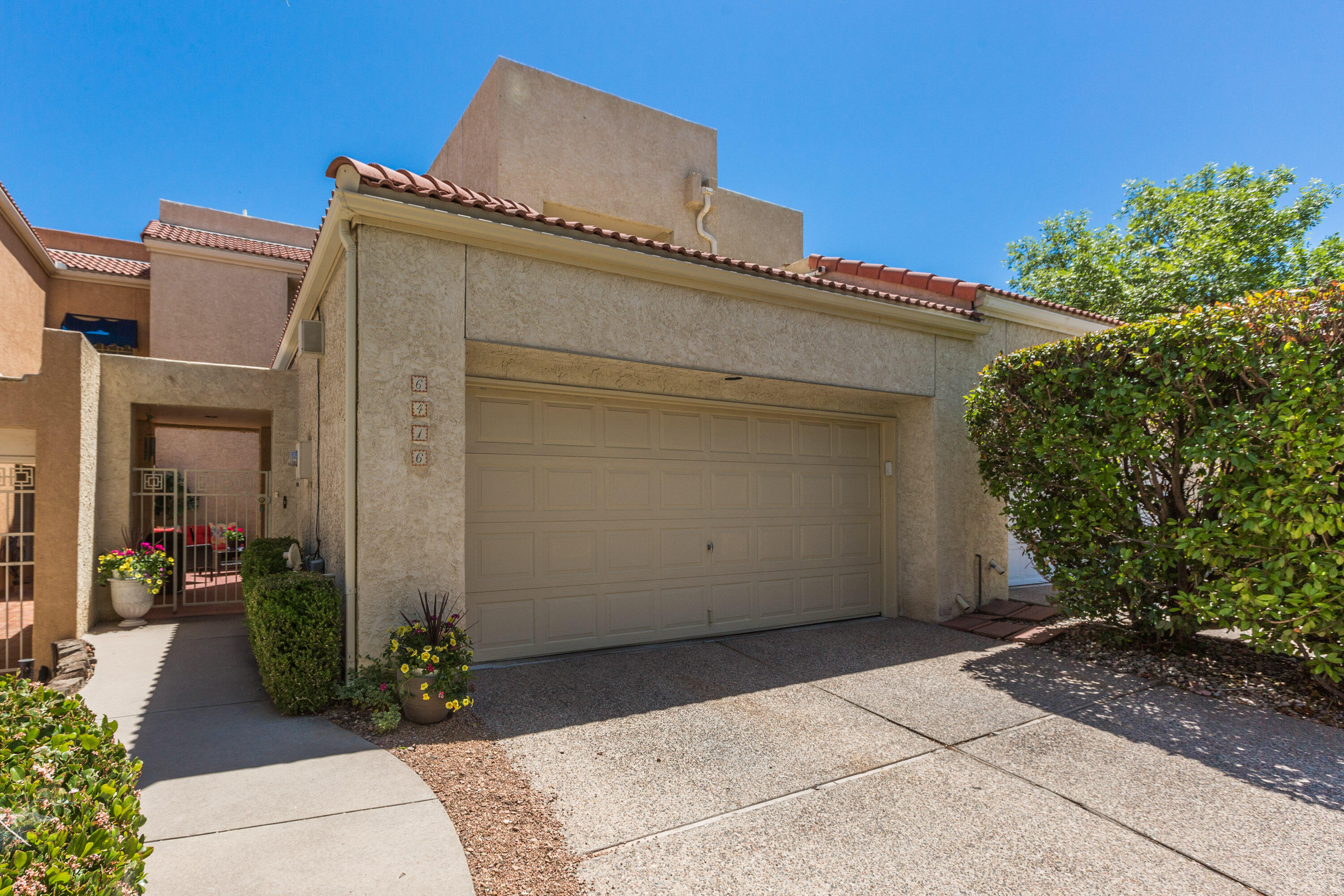 This incredible Townhouse is located in Albuquerque's only 24/7 guard gated golf course and country club community. Enjoy the privacy and security of this incredible community full of lush landscaping, mature trees and a beautiful golf course. This home has been lovingly maintained by the current owner and features many updates. Upon entering, you will be greeted by a private courtyard. Once inside, you will notice the soaring ceilings and large family room and dining room bathed in natural light. Over the last 5 years, updates include a TPO roof, stucco parapets, new air conditioner, water heater, new flooring including carpet and tile, new appliances, and fresh paint. There are 2 primary suites, one on each level, and a loft that could be converted to a third bedroom.