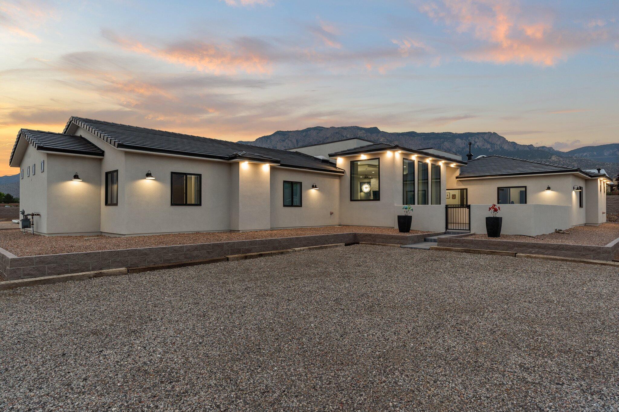 Thoughtfully placed with the backdrop of the Sandia Mountains, this home offers unparalleled views from every angle. This distinguished custom built home seamlessly blends luxury, functionality, and fine craftsmanship. The home sits on .89 acres and boasts 3 bedrooms, a charming guest house, theater room, a gym, and an office! You'll enjoy luxury amenities like zoned radiant heat, custom cabinets, a service pantry, quartz countertops, coffered ceilings, custom accent lighting inside and out, 2 cozy fireplaces, ample storage options, oversized 4 car garage, and an incredible outdoor space. The resort like backyard has a large covered patio, a sparkling pool, a fenced garden, a designated dog run, side yard access, built in grill area, and incredible views that redefine outdoor living!