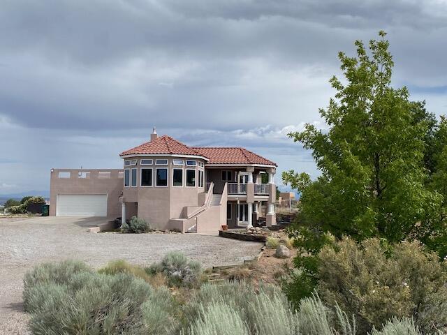 Custom home on an extra-large lot features a living room, dining room, kitchen and primary bedroom on the upper level. Hurd wood windows capture stunning views of the Rio Grande Valley, Mt. Taylor, Sandia Mountains, sunsets and balloons. Dine next to the two-way fireplace shared with the living room or outside on large covered balcony. The kitchen boasts solid oak slab cabinets with ample storage, two built-in microwaves, two dishwashers, a Sub-Zero refrigerator (2019), and a separate Sub-Zero freezer (2019) all blending seamlessly into the cabinetry. The lower level features a large living area with access to another covered patio, a second primary bedroom, three additional bedrooms and two full bathrooms. All bedrooms have direct access to outdoor areas.  New paint and carpet throughout