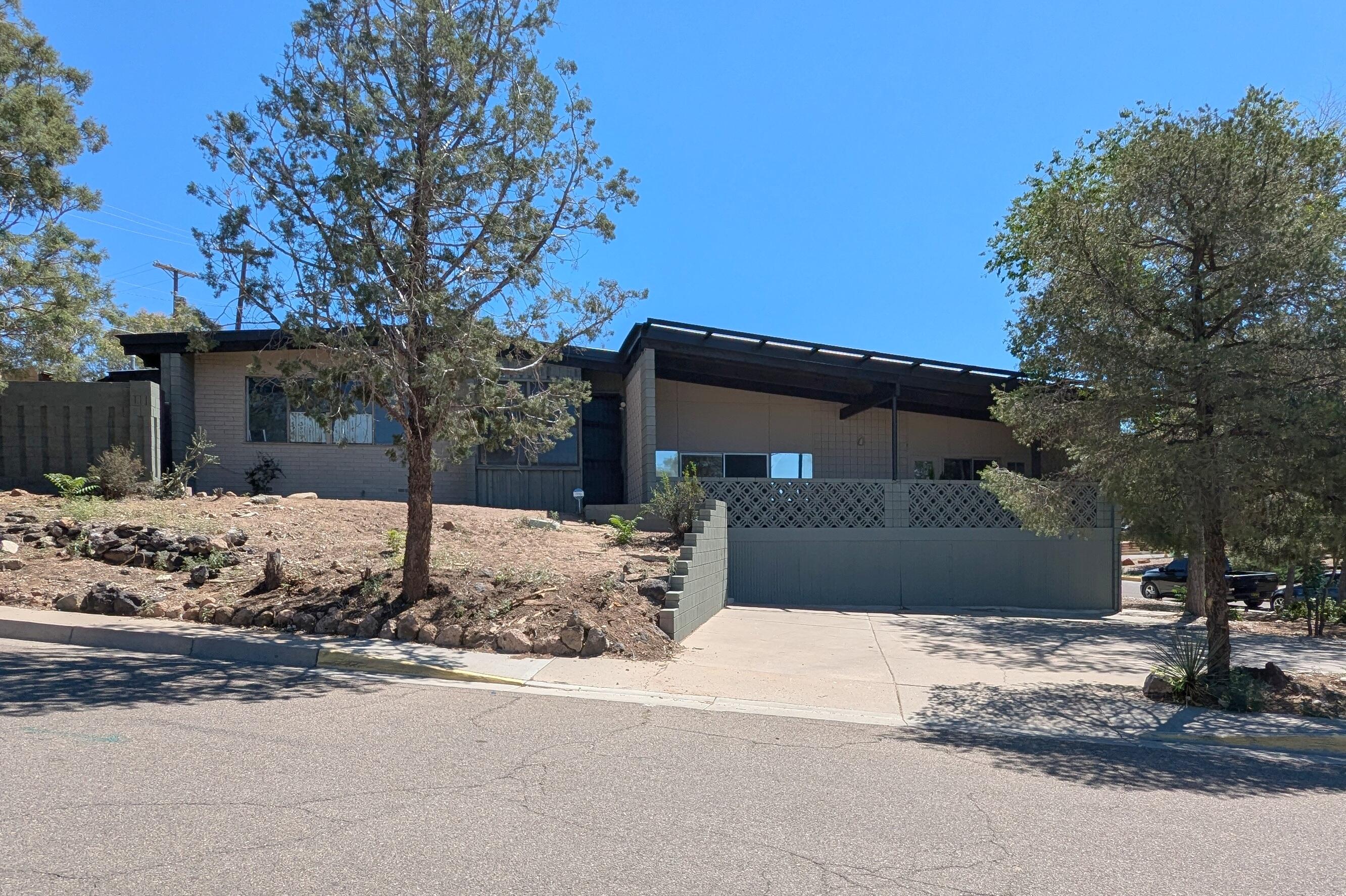 Featured on the front page of the 1961 New Mexico Home Show, Custom 2 story Mid Century Modern on a double lot. Designed by Louis G Hesseldon who designed many APS schools including Albuquerque High School, Nob Hill shopping center, Bernallillo County Courthouse and Hall of Justice, proposed Sandia High School, member of the AIA review board, Designed for Dr Robles of UNM.  Hesselden retained the position of sole architect for the school system until the 1950's. Priced aggressively to allow you to make it your own and bring it back to it's former glory. Many original features remain including an expansive game room with wet bar, 500 square foot covered deck with unobstructed city/sunset views.  Four bedrooms, two fireplaces, pool, atrium, large parking area.