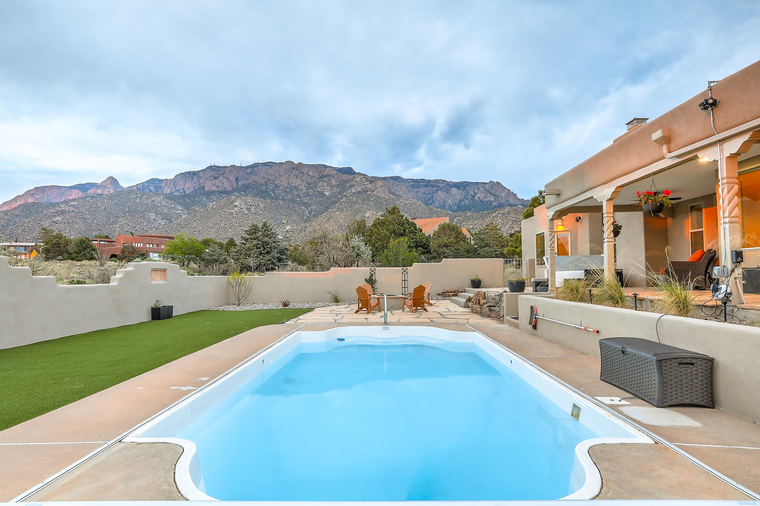 Located  in the serene Sandia Heights  neighborhood, this contemporary take on a classic Pueblo style home provides a relaxing spa getaway and an entertainer's paradise. Interior renovations include an updated modern kitchen featuring beautiful waterfall countertop with Cortona gold quartz, wine cooler, updated cabinets, and new paneled appliances. There is a built-in laundry area, and a fully equipped, and updated In-Law quarters with its own kitchenette, 3/4 bath and walk-in closet. The primary bedroom and en suite bath are  luxurious and spaciously appointed with silver travertine heated tile floors, a separate vanity dressing area, his/her sinks  and a full walk-in steam ready shower. A spa inspired backyard is ready for entertaining.