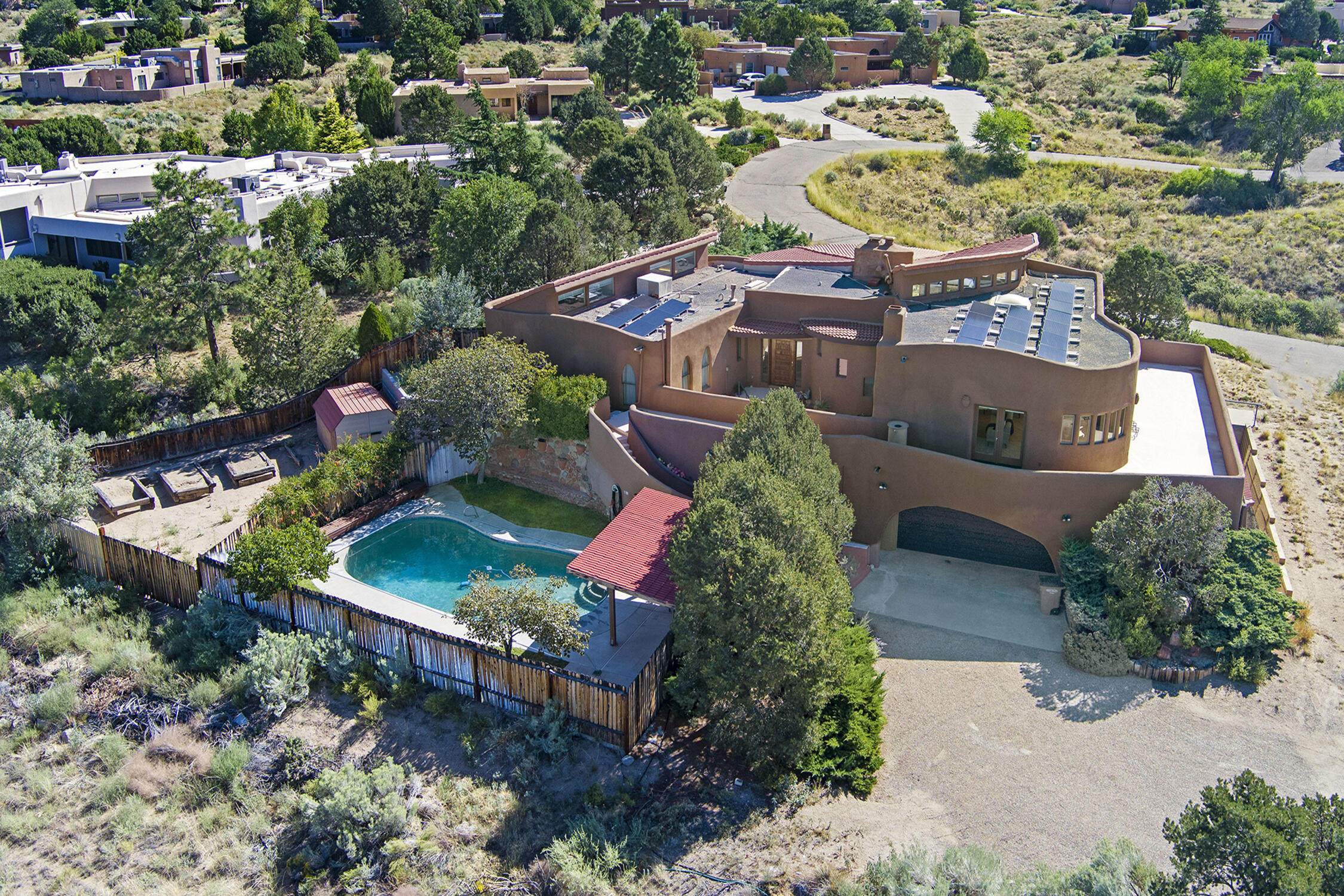 One of a kind opportunity on this dynamite Sandia Heights original owner gem!  Unparalleled city & Mountain VIEWS! Extremely energy efficient with slump rock filled concrete plus 4 inches of insulation to make up the 12 inch think exterior walls,  passive solar trombe wall PLUS owned solar installed 2021.  Further recent improvements include stucco and updated kitchen and bathrooms.  Custom  cabinets are made of red oak, calcutta gold quartz counters in kitchen and baths. The main home is comprised of over 3600 sq ft with 3 bd, 2.5 bath and two spacious living areas perfect for entertaining.  The lower level (off 5 car garage + large workshop) has its own access and offers an additional 718 sf heated living space with another LARGE bdrm, living space and full bath.