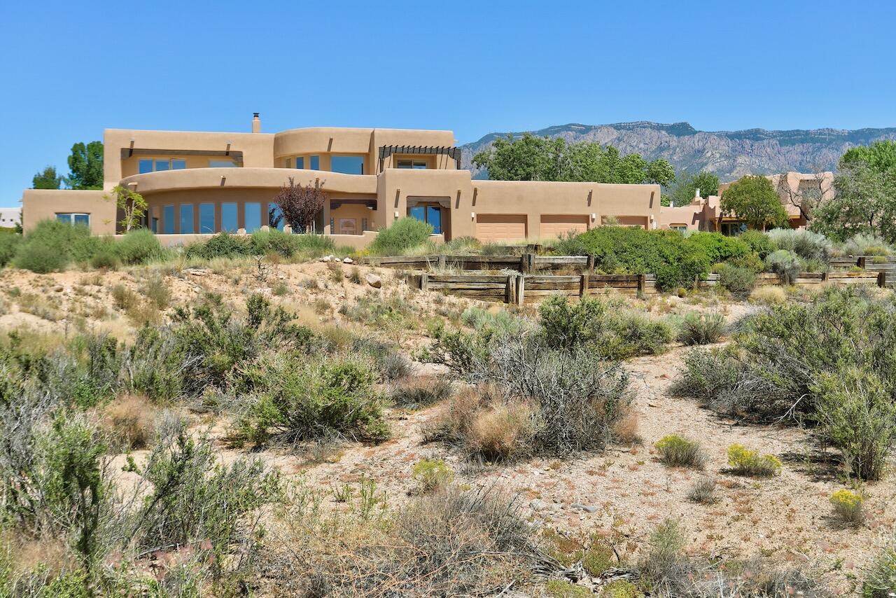 Beautifully Designed Contemporary Pueblo Situated on an Elevated View Lot in North Albuquerque Acres * The Floor Plan is Highly Flexible with an Option for 4 or 5 Bedrooms * Light Filled Living Room with Curved Wall of Windows and Custom Kiva Fireplace * Kitchen Built for Cooking with a Large Island, Generous Number of Cabinets , Breakfast Bar, Dining Area and Granite Counters * The Den Flows with The Kitchen and Has Mountain Views * Rec Room is Tucked off the Den with Outside Access  and a Wall of Storage * Spacious Primary Bedroom Contains a Sitting Area or Work Out Space * Primary Bath is Well Laid Out with Separate Tub, Glass Block Accented Shower , Double Vanity and Corner Window Framing a Mountain View *  3 Car Garage with One Bay Separated as a Workshop * Beautiful, Grassy Yard