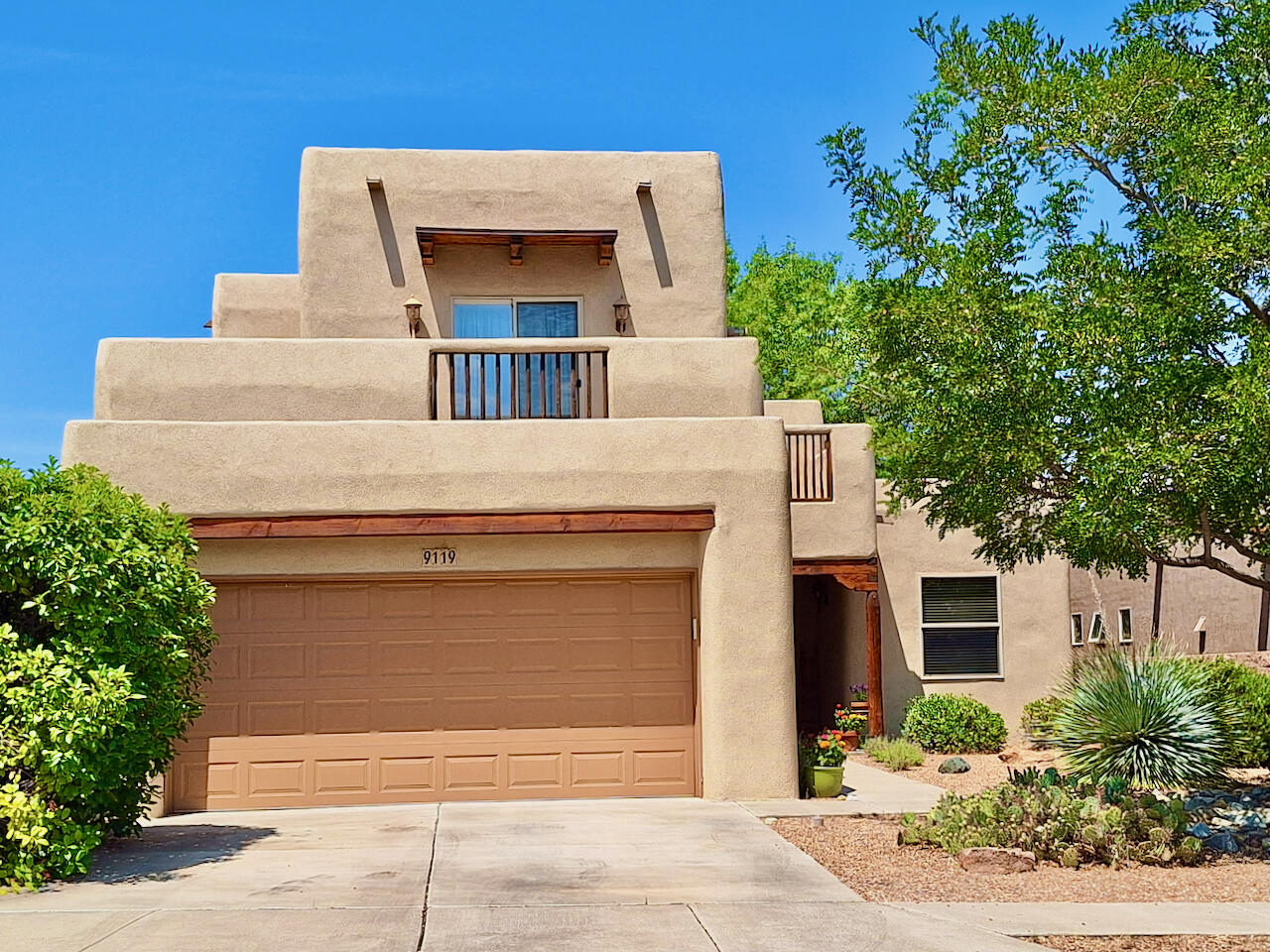 Custom Gallipoli home with charming southwestern touches, including a kiva-style fireplace with Banco, tongue & groove pine ceilings, vigas, corbels, & copper-trimmed beams. Open floor plan features tall ceilings, tons of natural light & sunset views through wall of windows. Kitchen boasts maple cabinetry, tiled counters, breakfast bar, pantry, & newer (2024) stainless appliances. Quality 2x6 construction with solid pine doors & stairs that lead to side deck with city/mountain views. Large owner's suite boasts a FP & opens to deck with Sandia views. En-suite has walk-in closet, dual vanities, custom tiled shower & garden tub. Two main floor bedrooms, one with mtn views. Ref AC, radiant heat & wood/tile flooring - no carpet. Nicely landscaped front & back with covered rear patio & lawn.