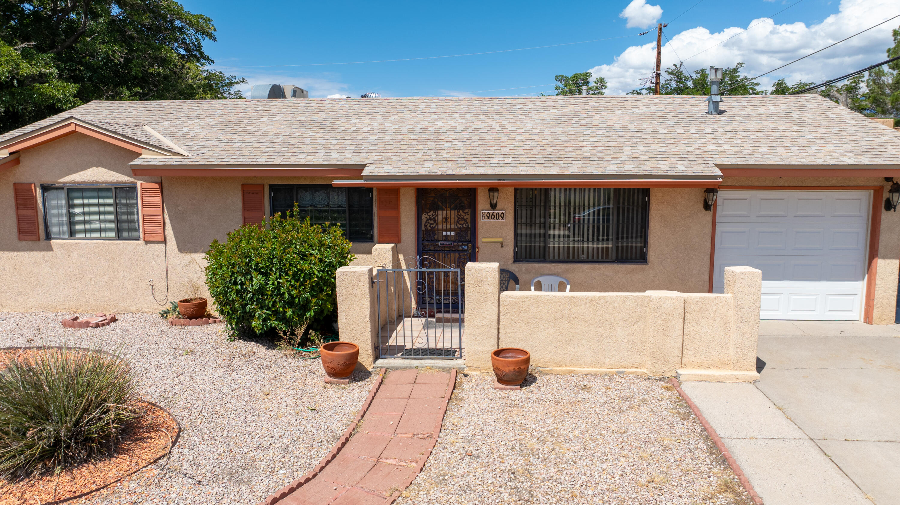 Lovingly cared for single owner home! Offering three bedrooms, two bathrooms, two living areas, separate laundry room, sunroom, single car garage and workshop. The kitchen opens into the dining/secondary living areas with built-in shelving and a gas log fireplace. Newer stainless steel appliances include the refrigerator, dishwasher and electric stove/oven. Additional updates include the master cool evaporative cooler and roof which were completed approximately seven years ago. The front and backyards are fully landscaped with Xeriscape, grass/lawn, trees and open patio. You'll love having the additional 487 s.f. workshop with electricity. Conveniently located close to ABQ Uptown, freeway,  parks and the Janet Kahn School of Integrated Arts Magnet Elementary.