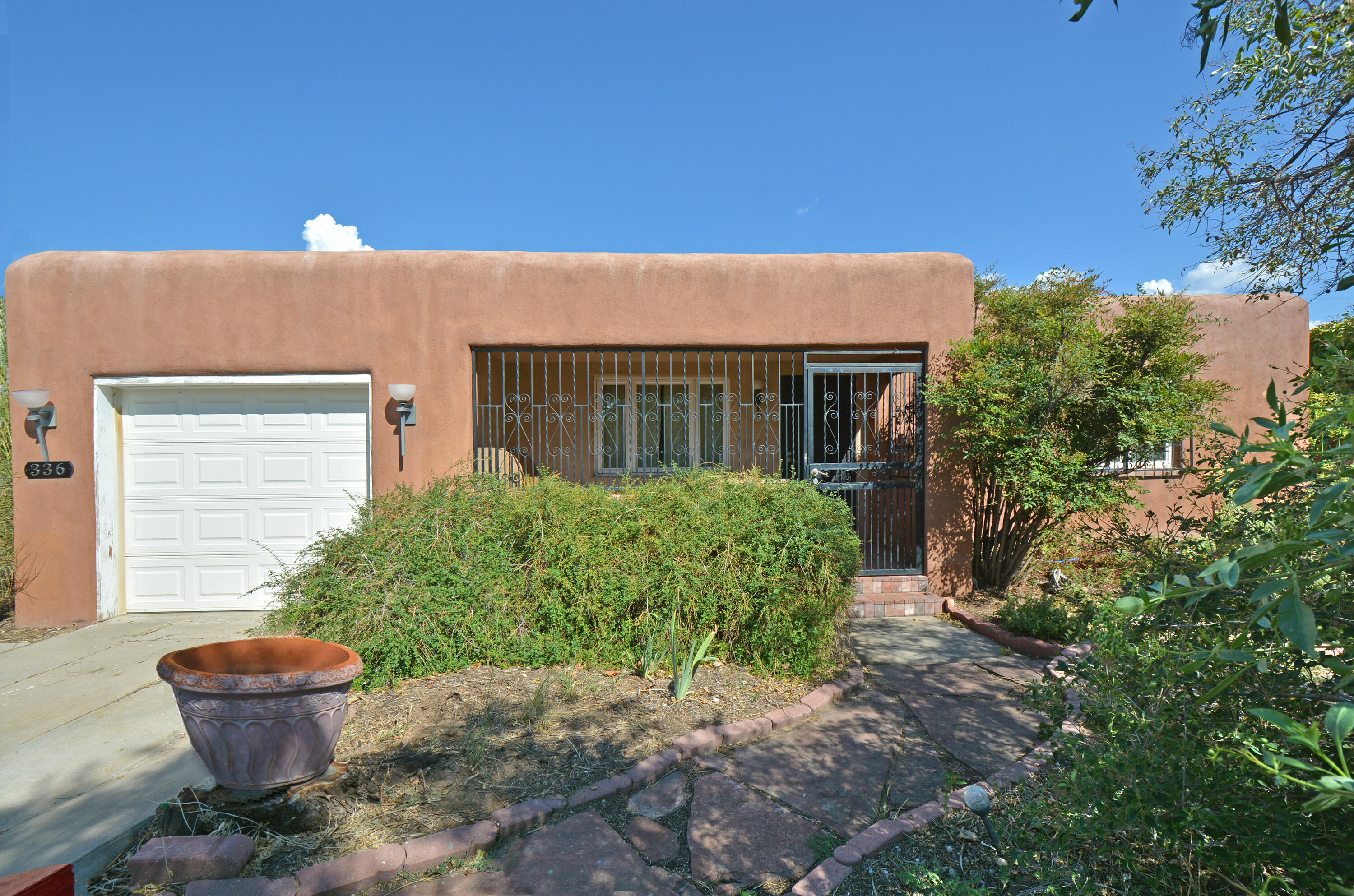 Spacious Pueblo-Style Home on quiet street. Beautiful refinished hardwood floors. Flexible floor plan with 2 bedrooms at the front of the home and the primary bedroom with a full bath  at the rear of the home. Cove ceilings and a  Gas log fireplace in the Living room.  Formal Dining room.  Maple cabinets and a slate floor in the kitchen. Skylights in both bathrooms and in the large utility room. Sitting room off of the kitchen with a slate floors and windows looking out to the lush backyard.  Newer double-paned casement and sash windows. 2 evaporative coolers. 1 car attached garage.  Large front porch. Attractive Security wrought iron with bedroom releases.  Lush shady landscaping provides a getaway in both the front and back yard. Large brick patio with built-in benches in the backyard