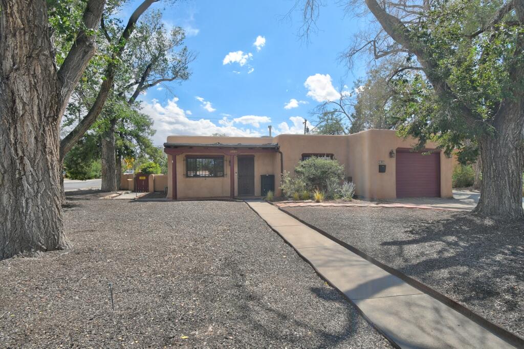 Wonderfully charming 4 BR Pueblo home featuring 2 kiva fireplaces, vigas, thick adobe walls, and saltillo tile. Spacious kitchen with breakfast nook, and separate dining area. The original front portion of the house has a furnace, refrigerated a/c and its own tankless water heater.  The primary and 3rd bedrooms were an addition many years ago, with radiant heat, evap cooling and another tankless WH!  The sellers have added 13 solar panels (owned) which provide amazingly low-cost energy bills. There is a newer  water softening system, including a reverse osmosis.  Three new electrical panels in 2022.  A lovely patio with Gazebo is off the kitchen; and a separate private courtyard in backyard. Situated on a corner with side yard access! Close to I-40 entrance and many other conveniences!