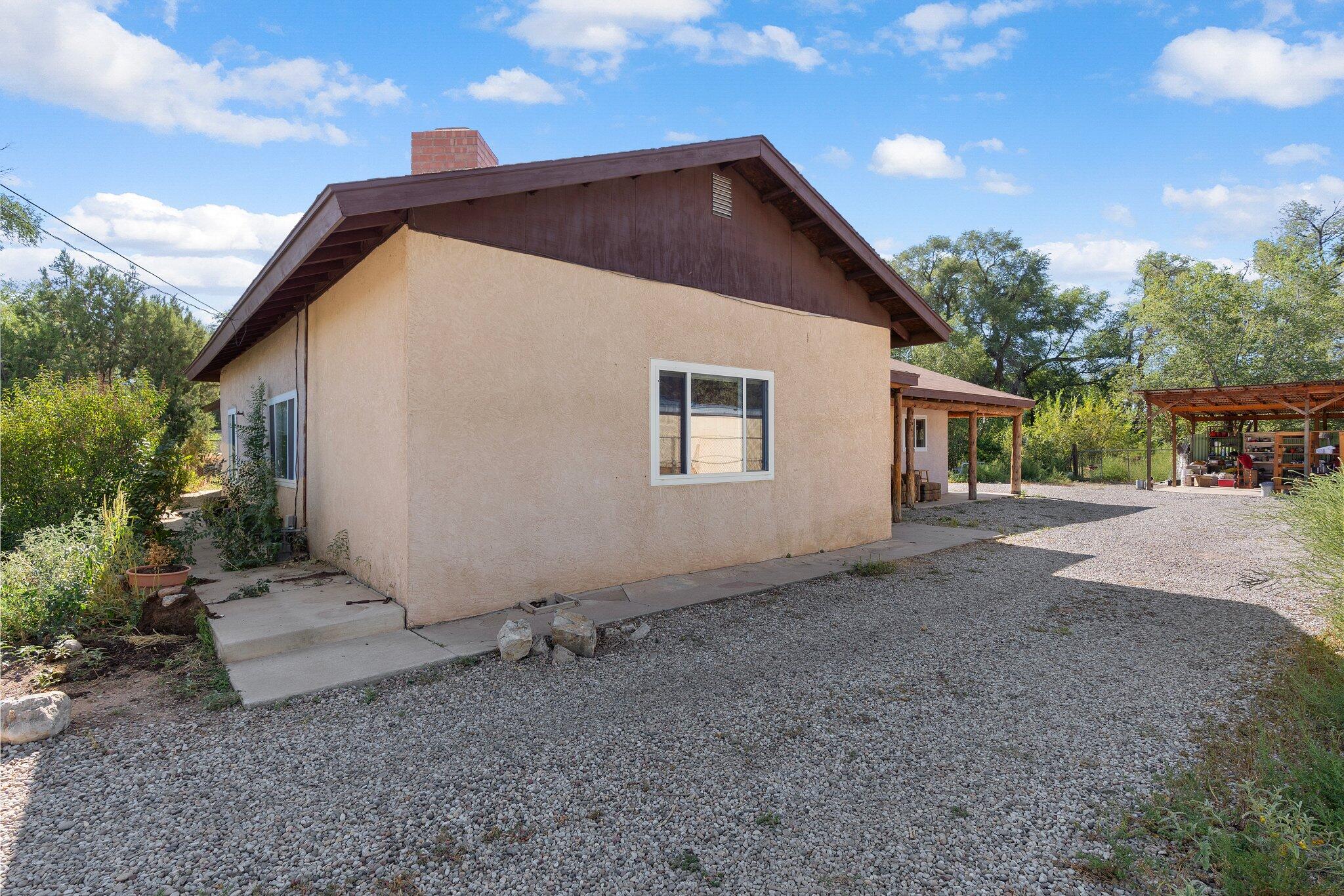 Your modern hobby ranch awaits! This single-owner property features multiple out buildings & hobby farm potential. Vintage character meets contemporary upgrades & amenities. Living area features tongue & groove ceiling, thick plaster walls w/radius corners & grand kiva fireplace. Lots of natural light through wide windows. Huge laundry/washroom w/built-ins. Generous galley kitchen with ample cabinet space & eat-in dining w/separate heat. Primary suite boasts custom slate tiling, walk-in closet & double doors to back patio. Wrap-around patios w/scraped latillas & al fresco dining space. Concrete pad car port perfect for hobbies, hay or anything else that needs to be covered. Large shed. Heated workshop. Securely fenced in charming Pajarito Village, close to acequias & the beautiful Bosque.